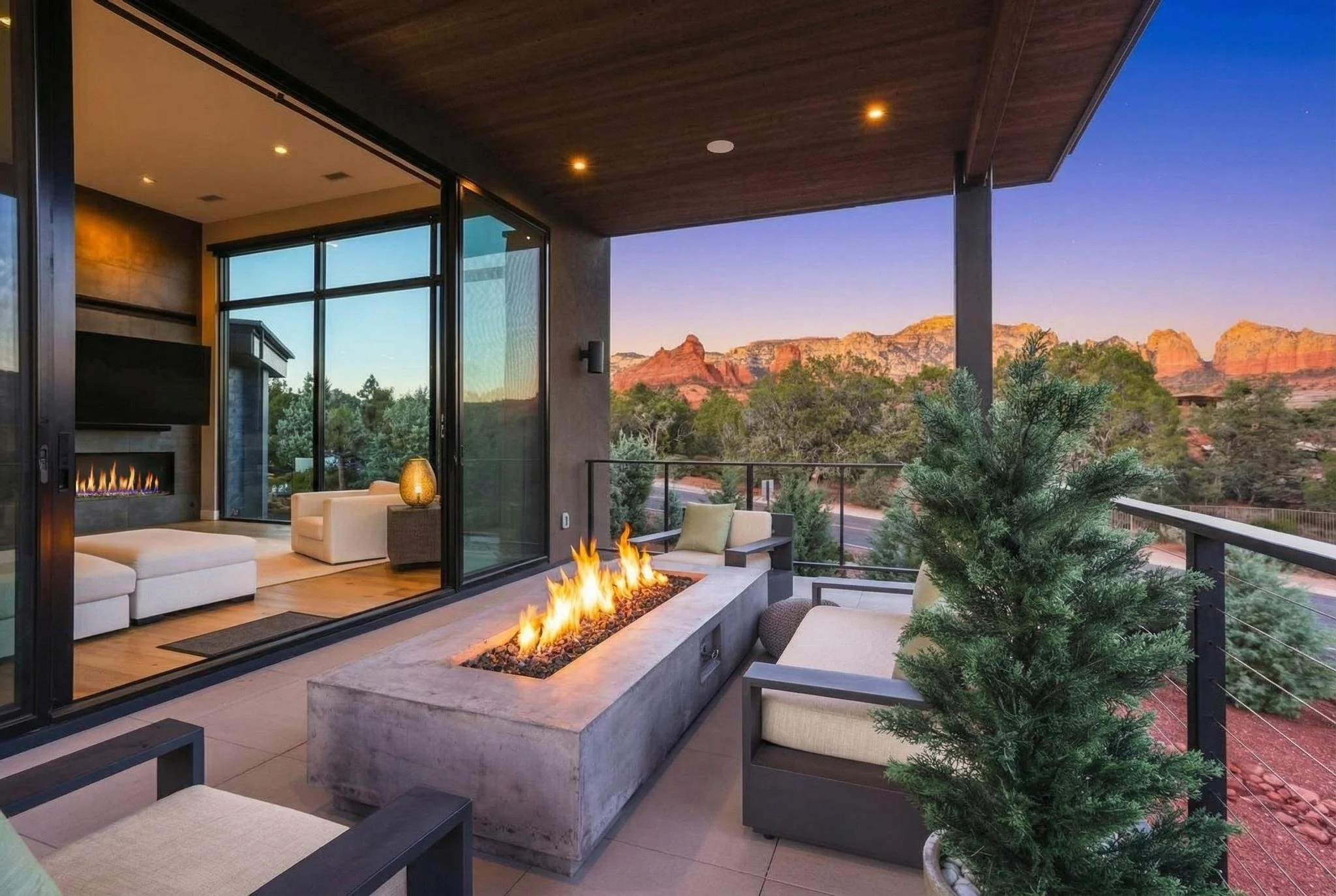 Outdoor balcony with fire feature, patio furniture, and view of mountains at sunset.