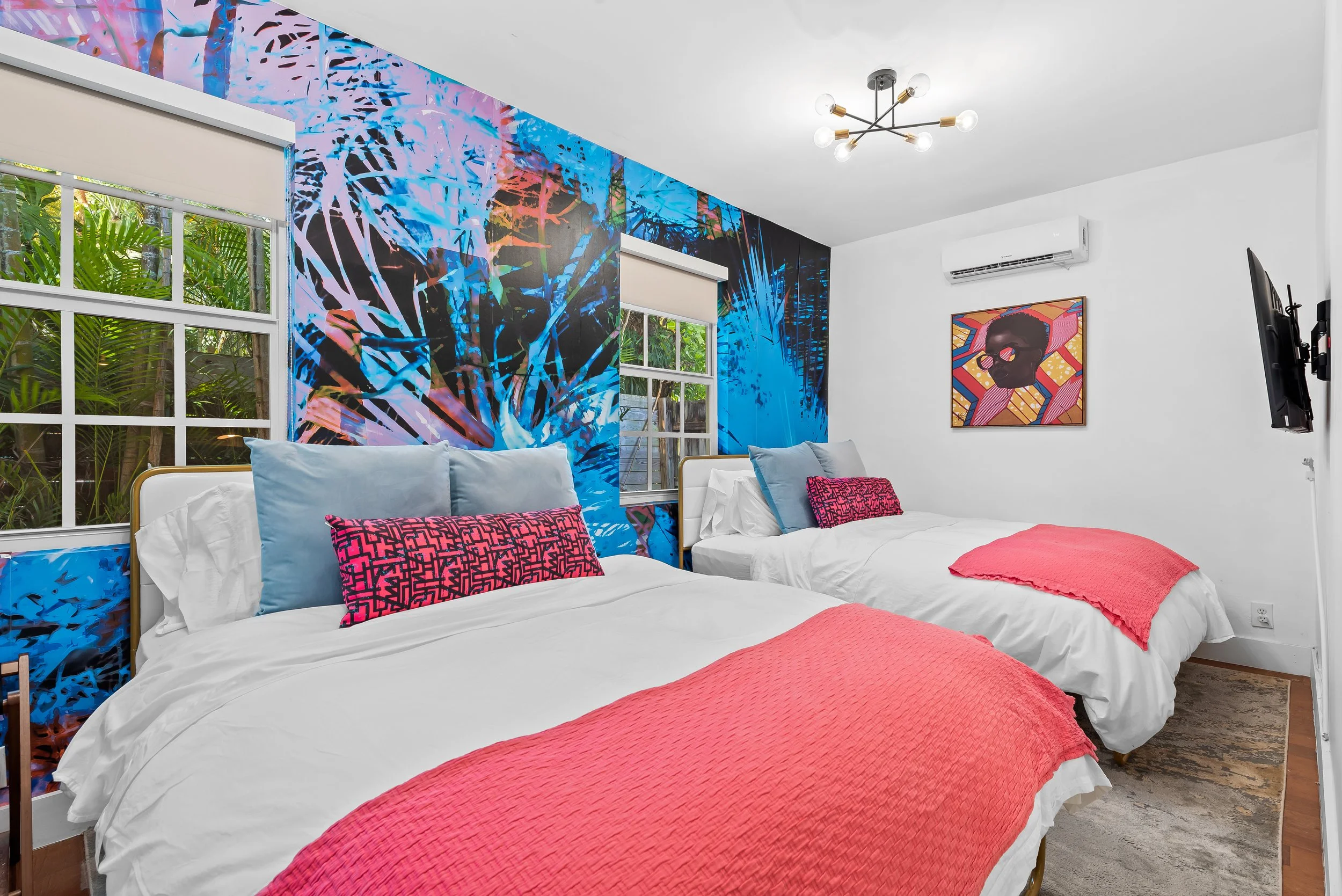 Twoe-bed room with coral pink accents and abstract wall art — Sun Haven Collection family vacation rental