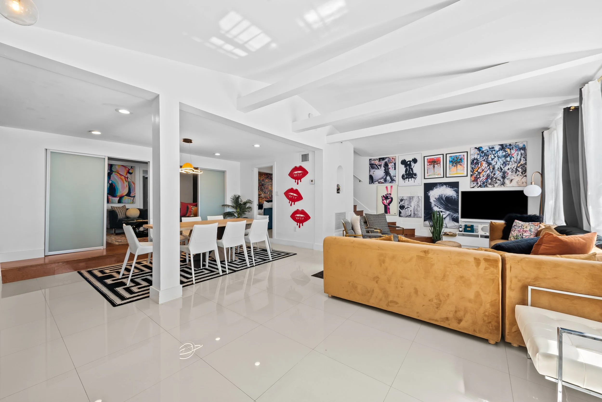 Open-concept living and dining with curated artwork and hardwood floors — Sun Haven Collection vacation rental.