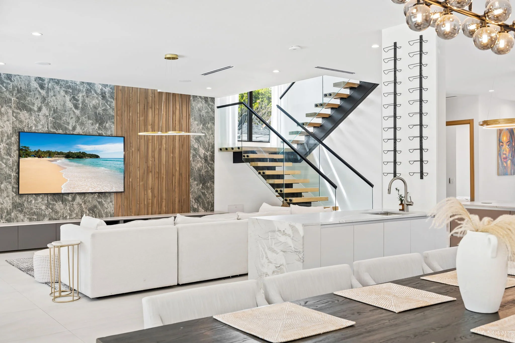 Luxury living room with designer lighting, marble feature wall, and glass staircase — Sun Haven Collection vacation rental.