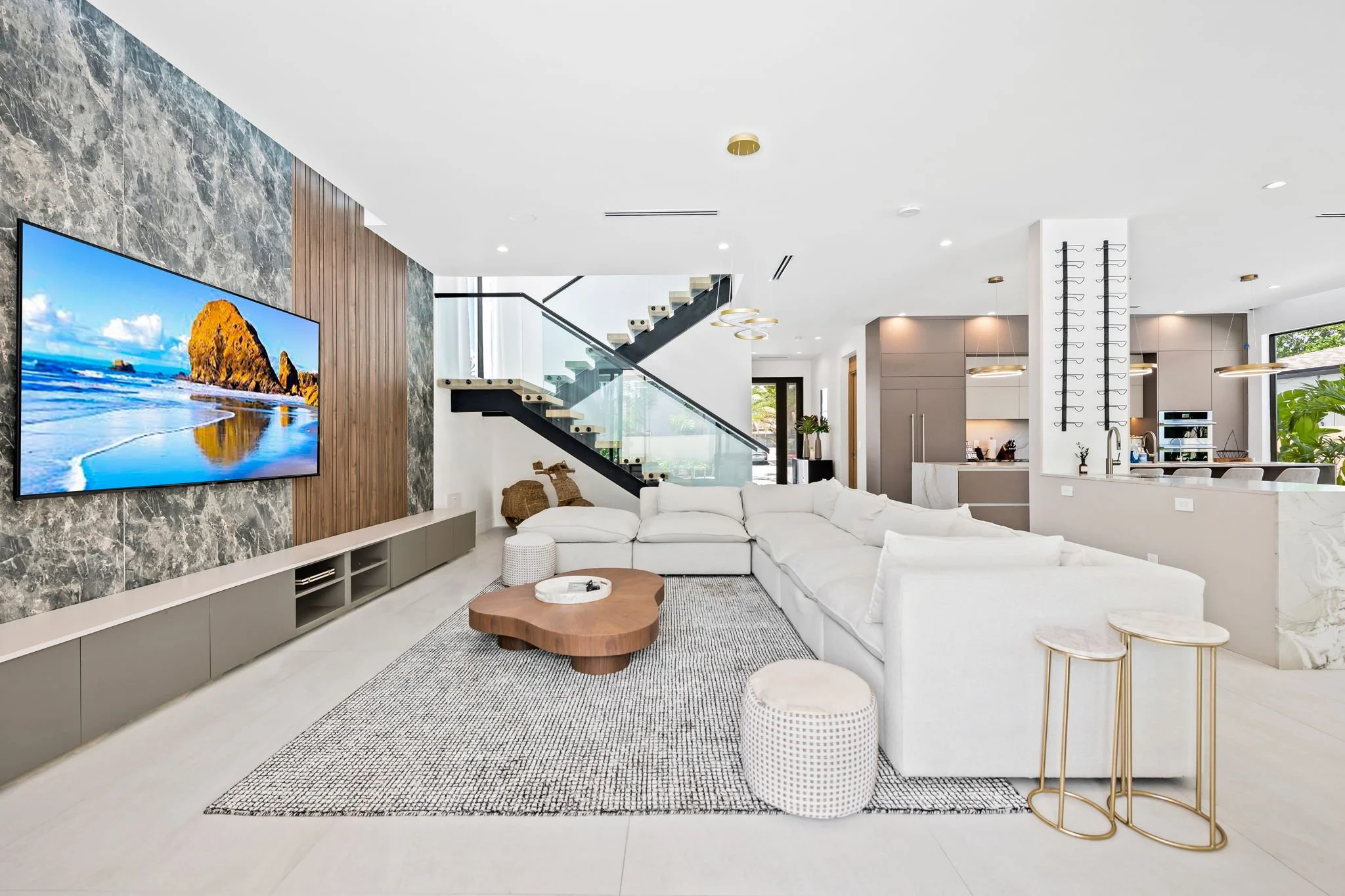 Open-plan living and kitchen with marble accent wall and designer pendant lights — luxury vacation home by Sun Haven Collection.