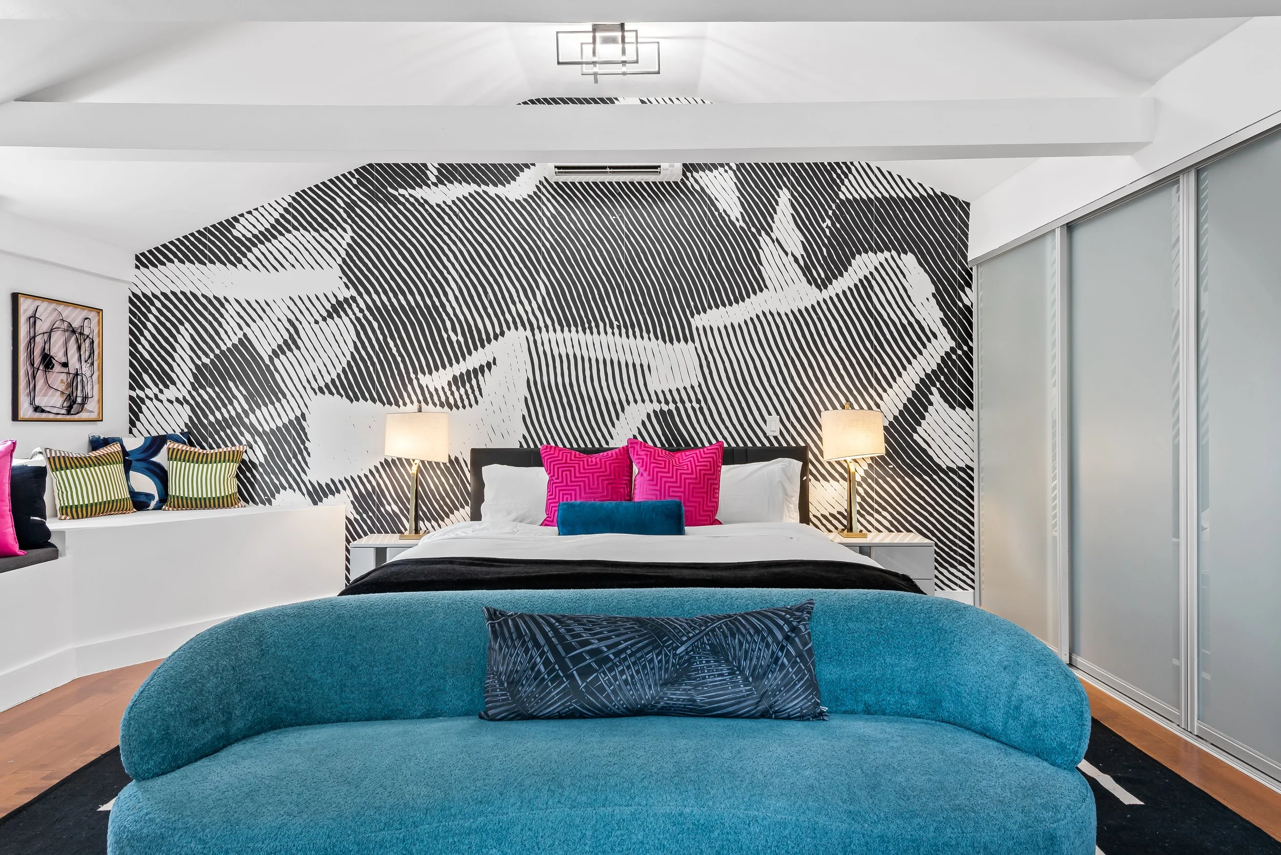 Designer bedroom with abstract mural and teal upholstered bed — luxury vacation rental by Sun Haven Collection.