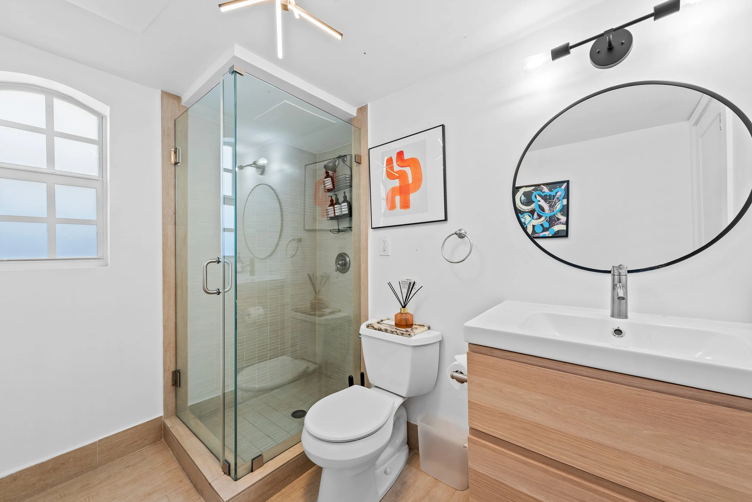 Clean modern bathroom with abstract artwork and wooden vanity — luxury vacation rental by Sun Haven Collection.