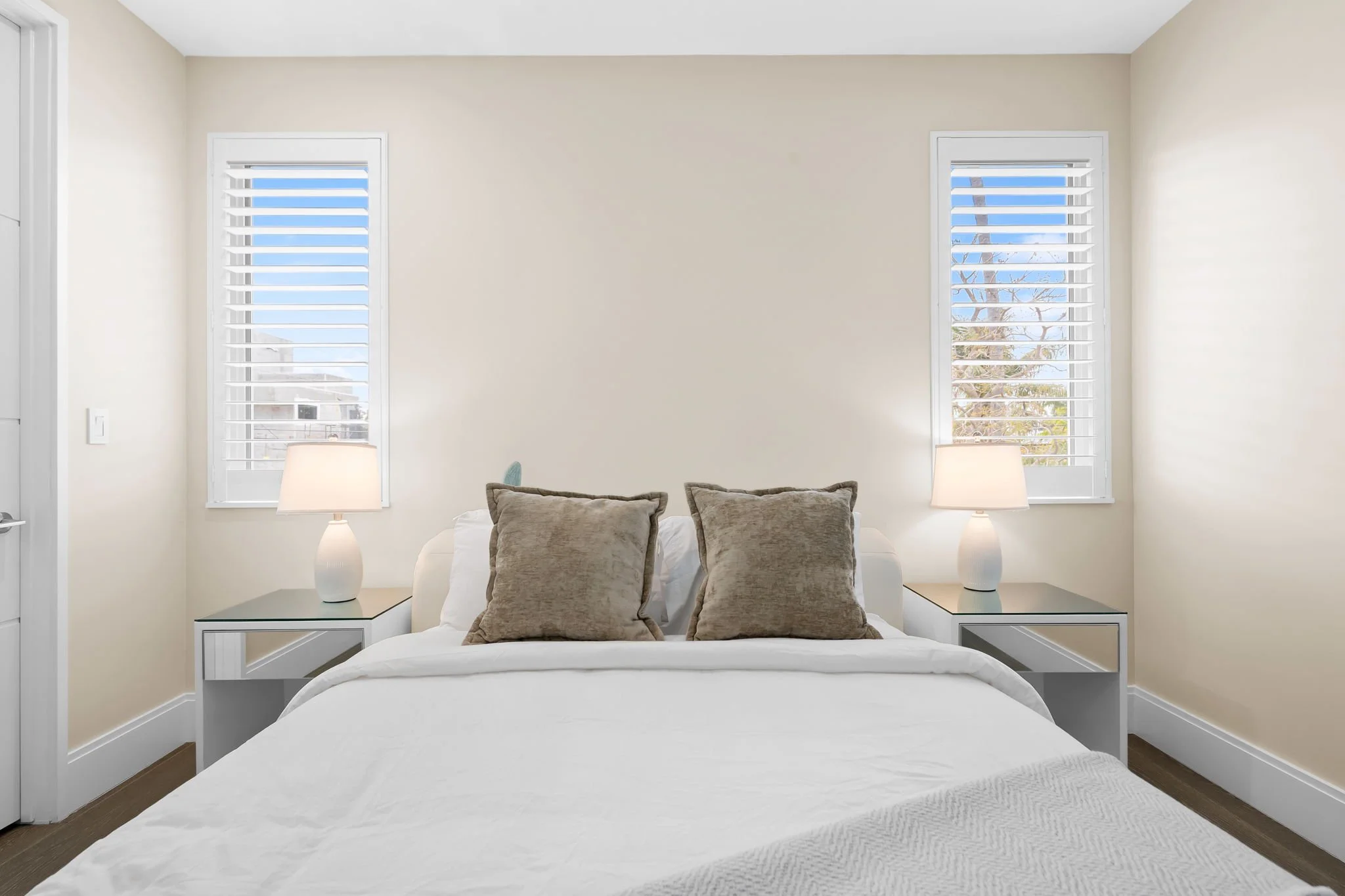 Sunlit guest bedroom with designer lamps and neutral tones — luxury vacation home, Sun Haven Collection.