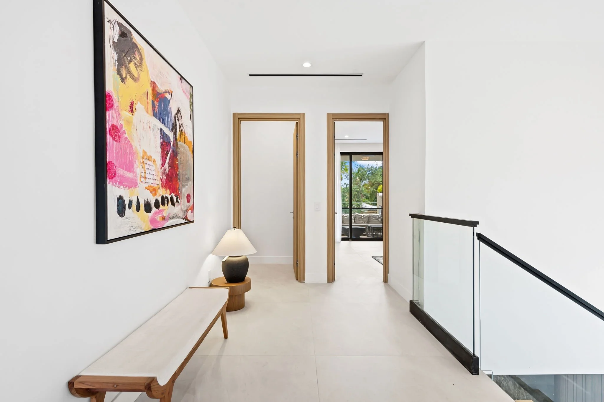 Gallery-style hallway with original artwork and balcony access — Sun Haven Collection luxury vacation home.