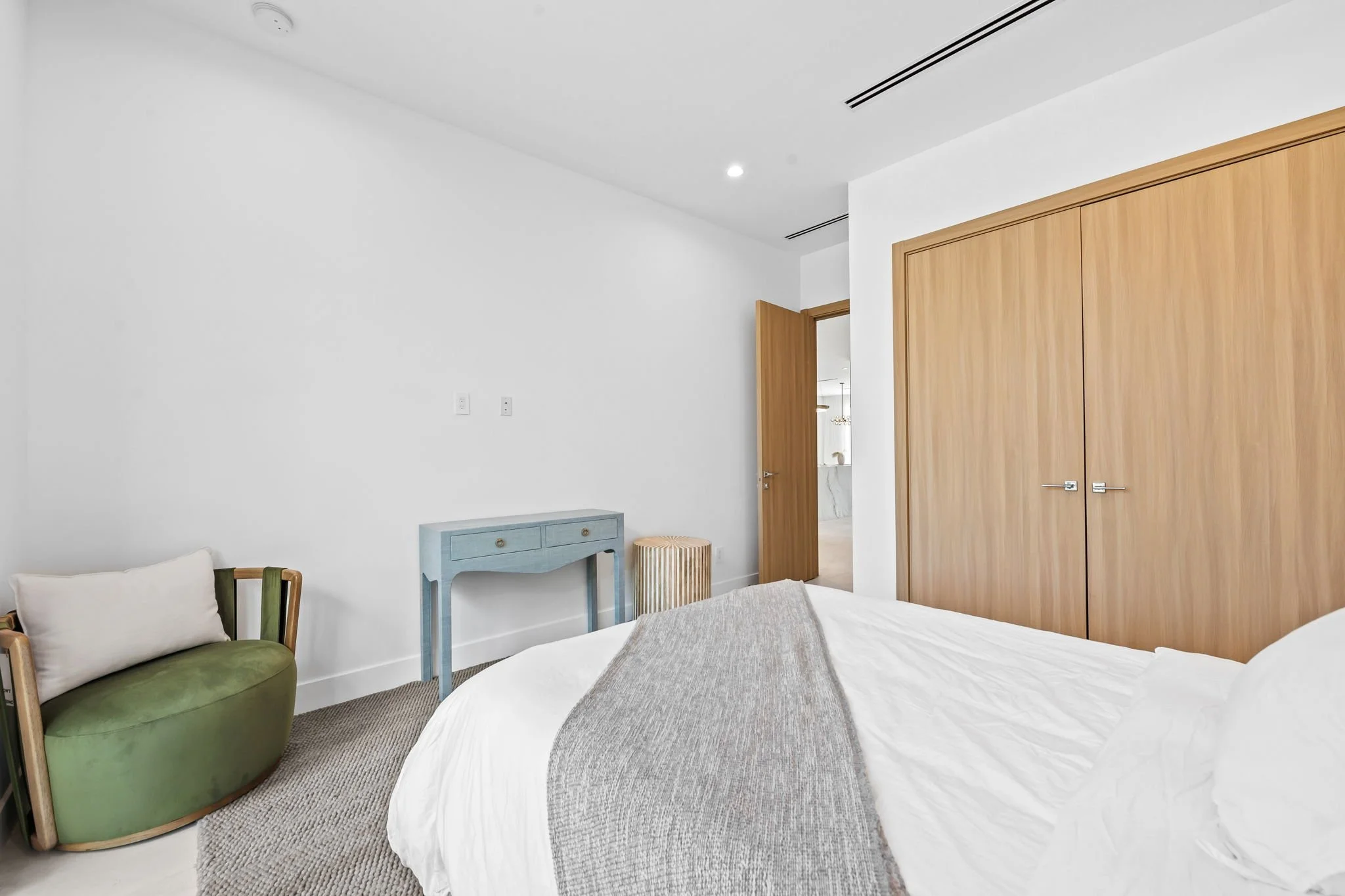 Stylish bedroom with designer accent chair and modern closets — luxury vacation home by Sun Haven Collection.