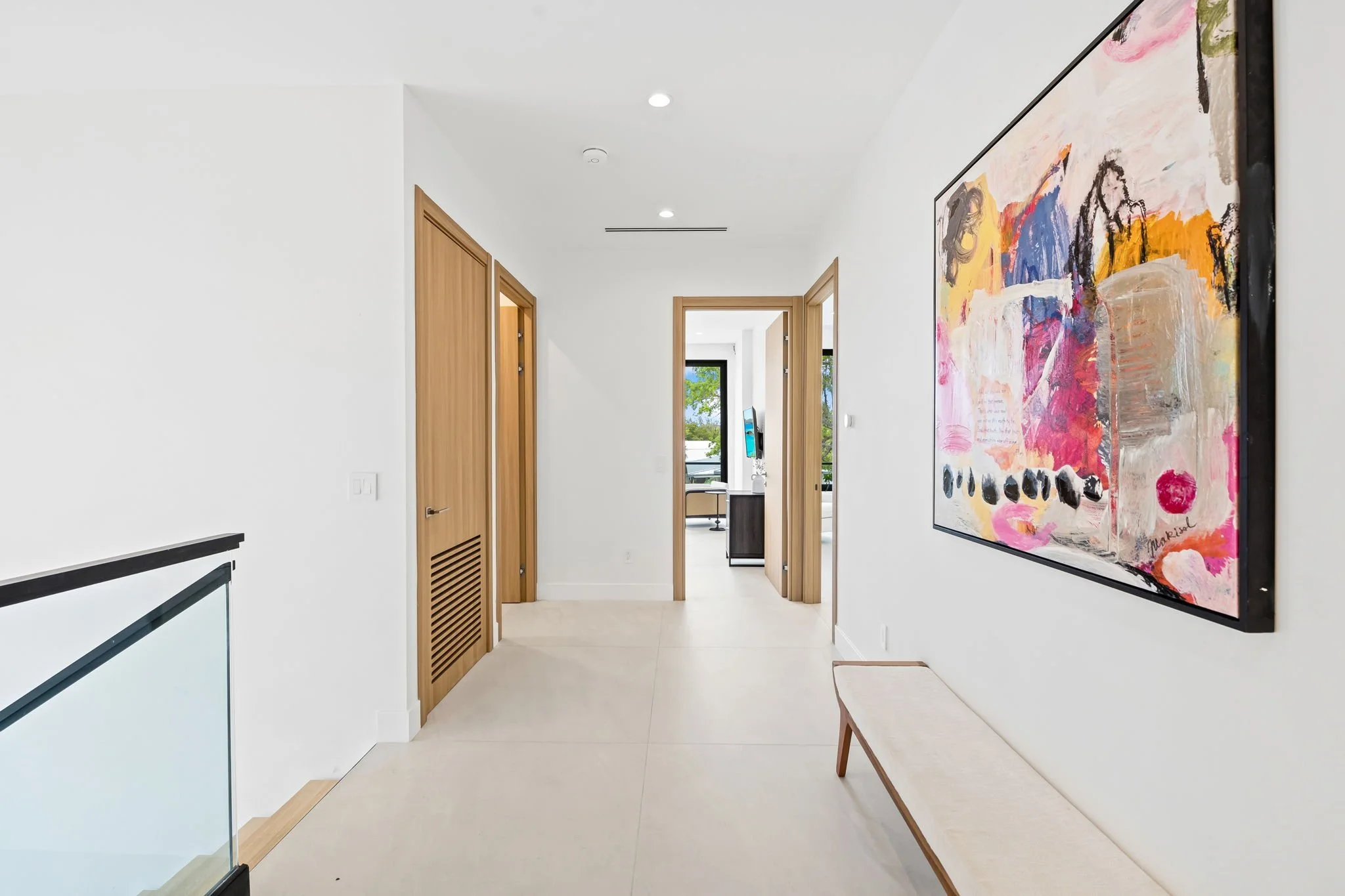 Light-filled hallway with colorful abstract art and garden views — design-forward vacation rental, Sun Haven Collection.