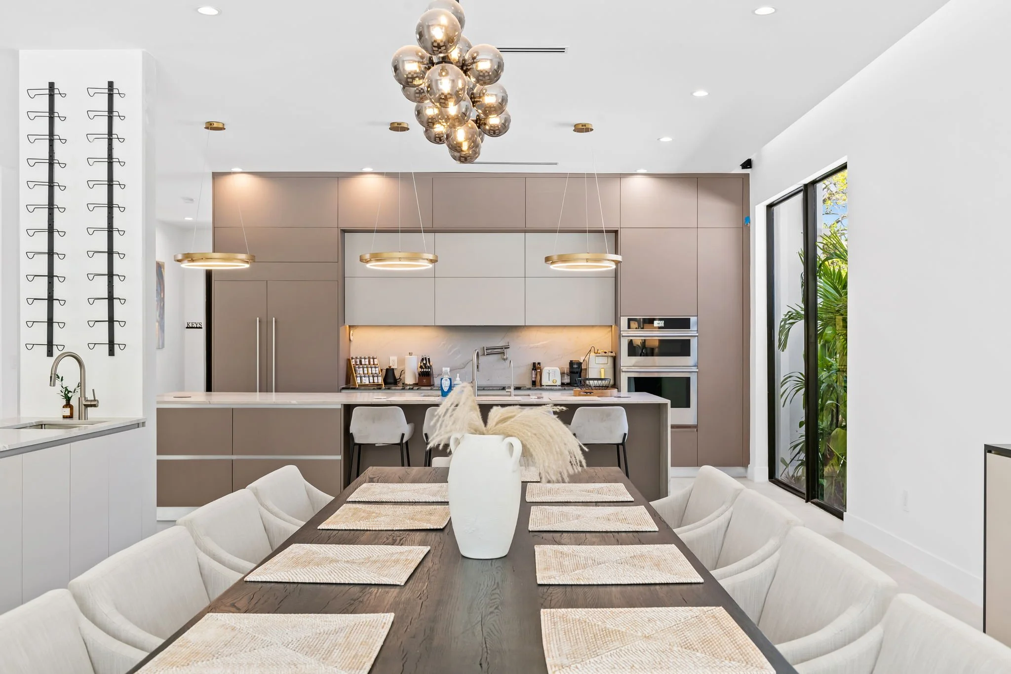 Modern kitchen and dining area with pendant lighting, designer cabinetry, and garden views — luxury vacation rental by Sun Haven Collection.