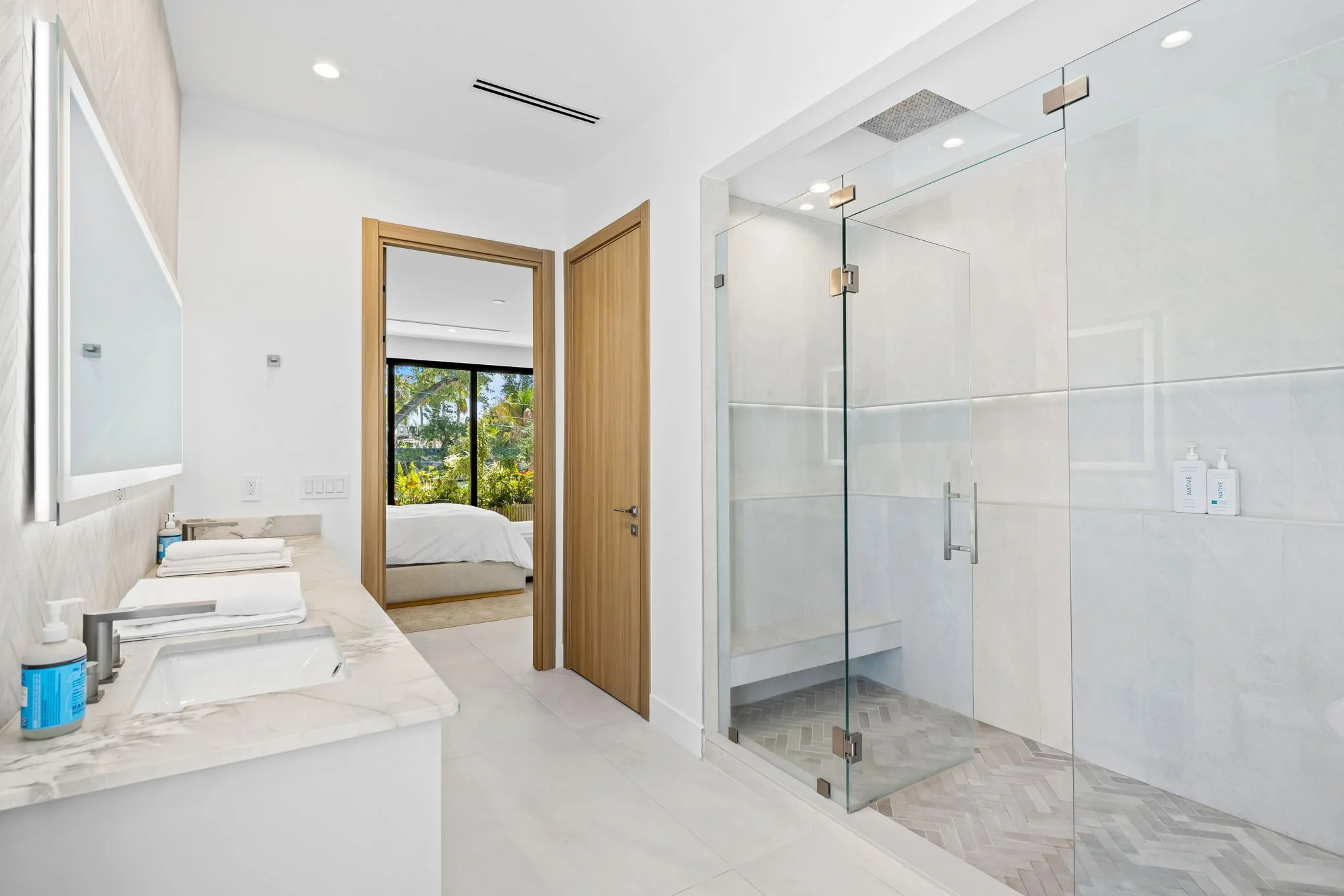 En-suite bathroom with marble vanity and garden views — design-forward vacation rental, Sun Haven Collection.
