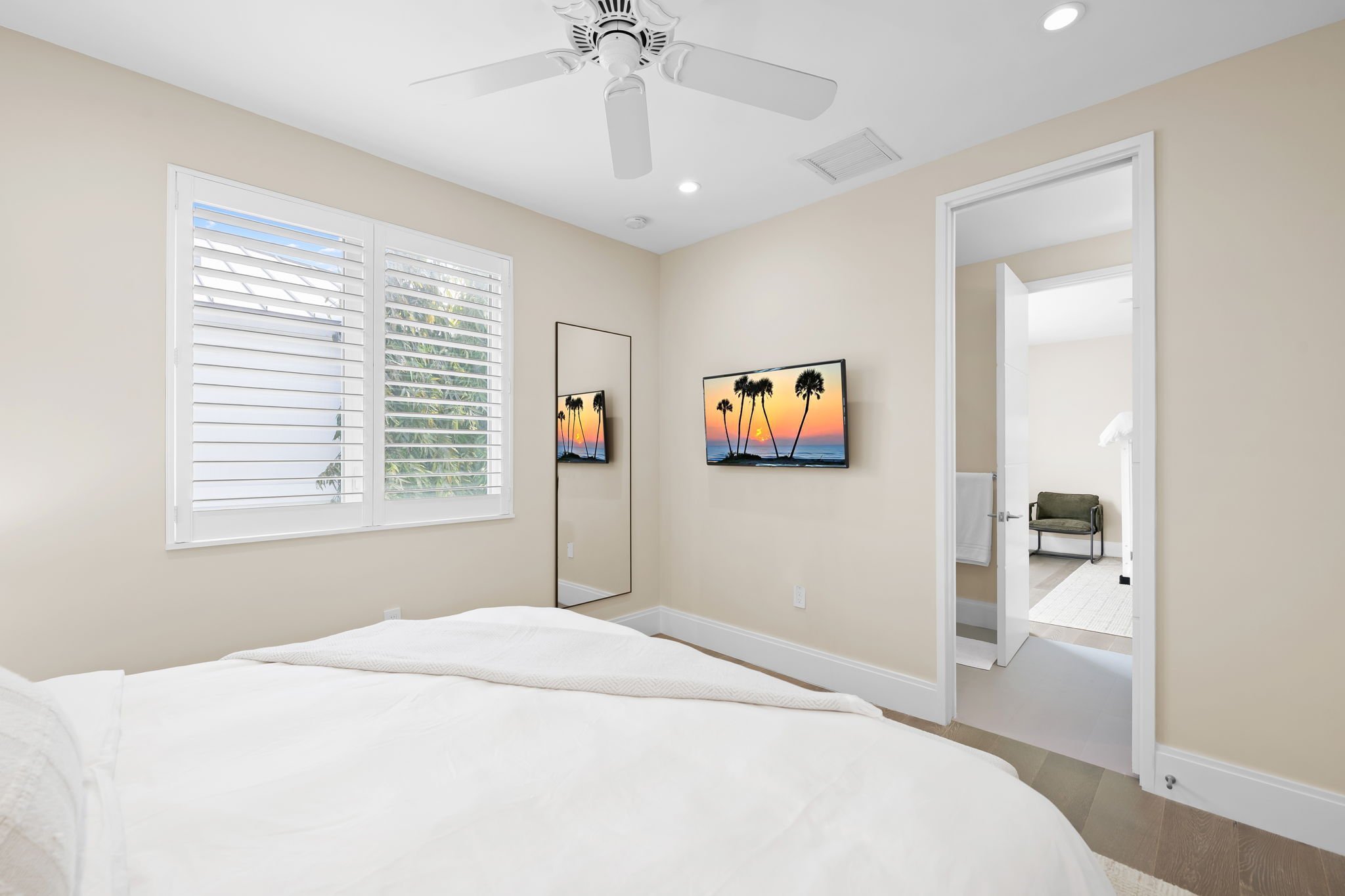 Entertainment bedroom with dual smart TVs and palm tree views — luxury vacation home, Sun Haven Collection.