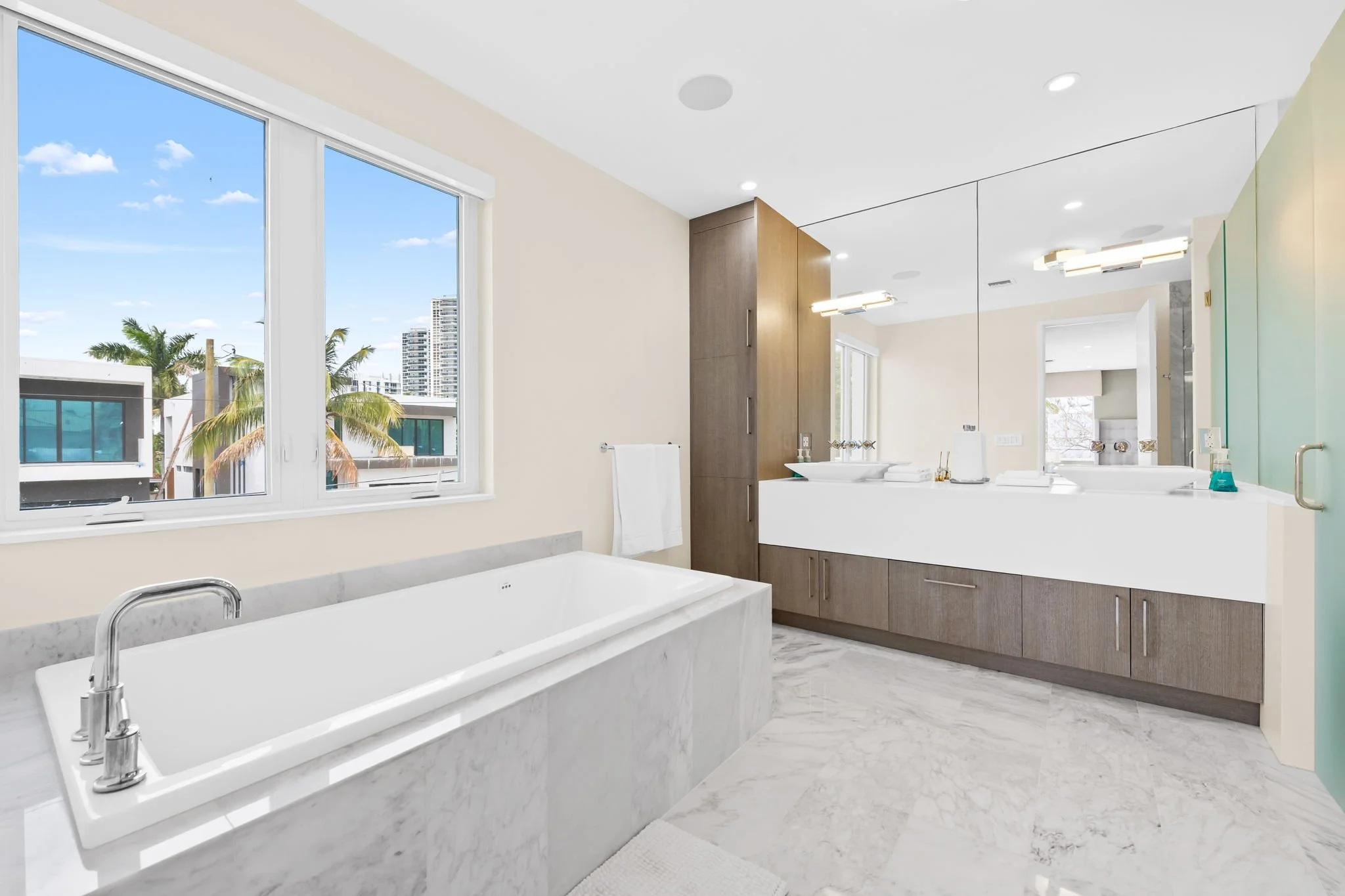 Spa bathroom with soaking tub and palm tree city views — Sun Haven Collection luxury vacation rental.