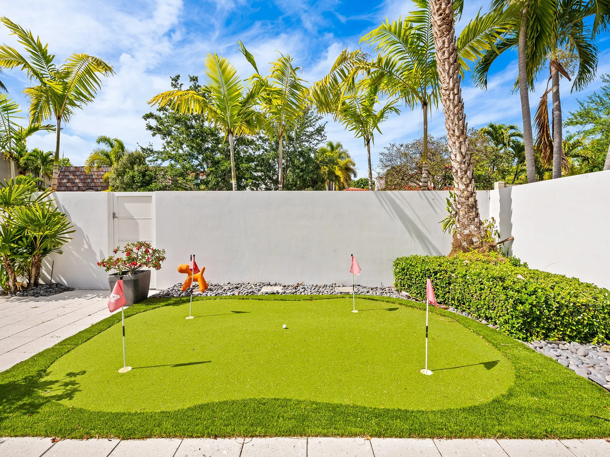 Private backyard putting green with palm trees — Sun Haven Collection luxury vacation rental amenity.