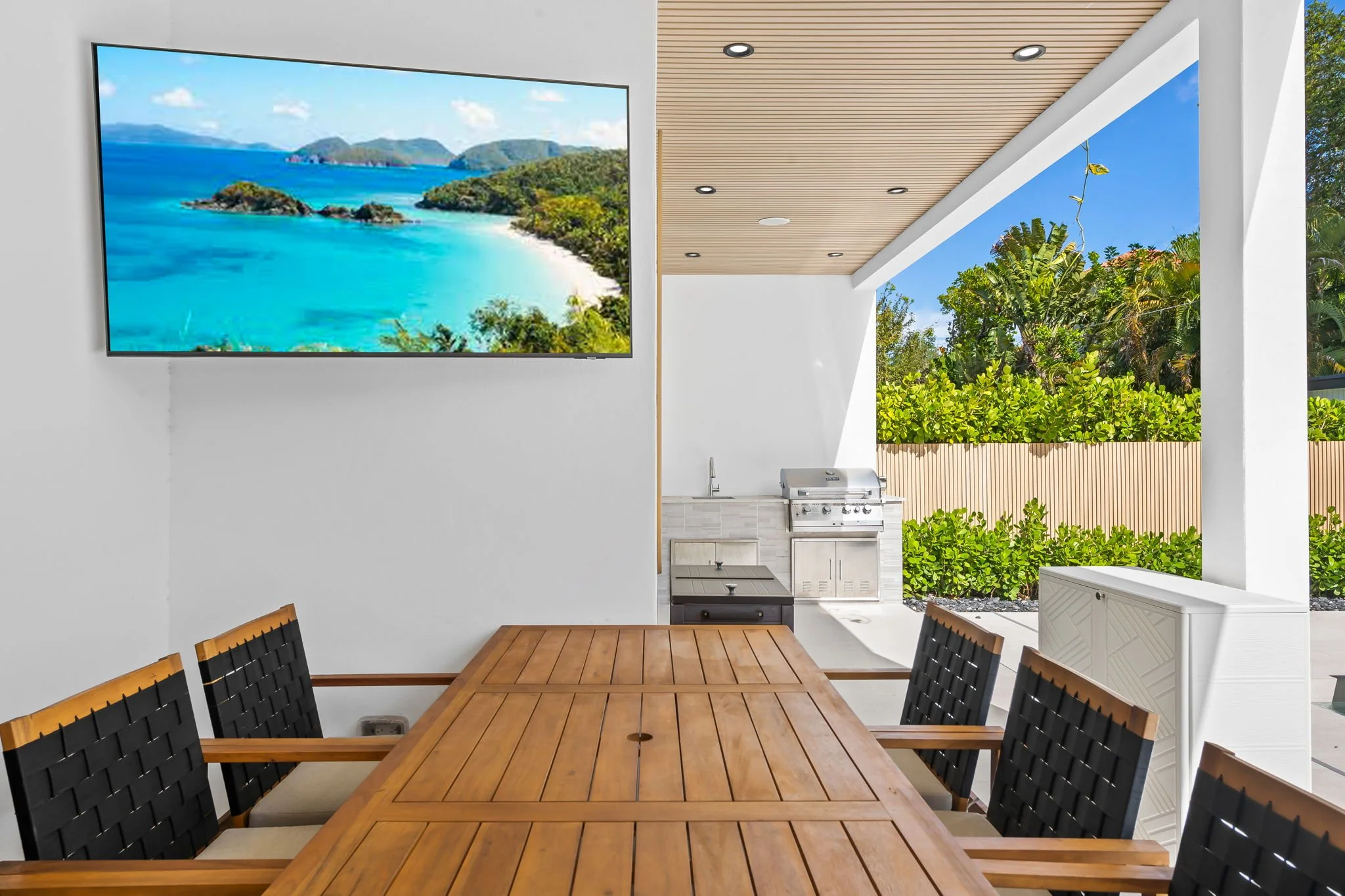 Covered outdoor kitchen with built-in grill and tropical garden views — Sun Haven Collection vacation rental.