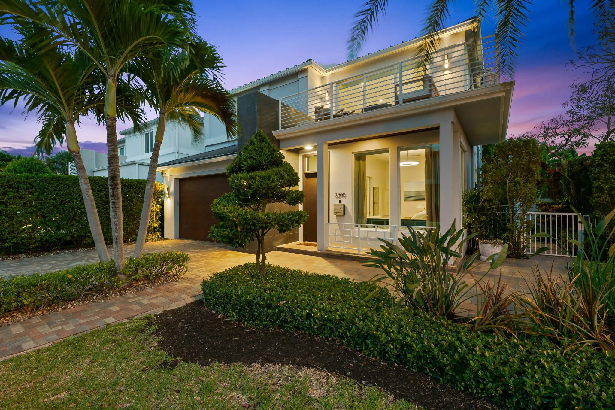 Luxury vacation home illuminated at dusk with tropical landscaping — Sun Haven Collection, Fort Lauderdale.