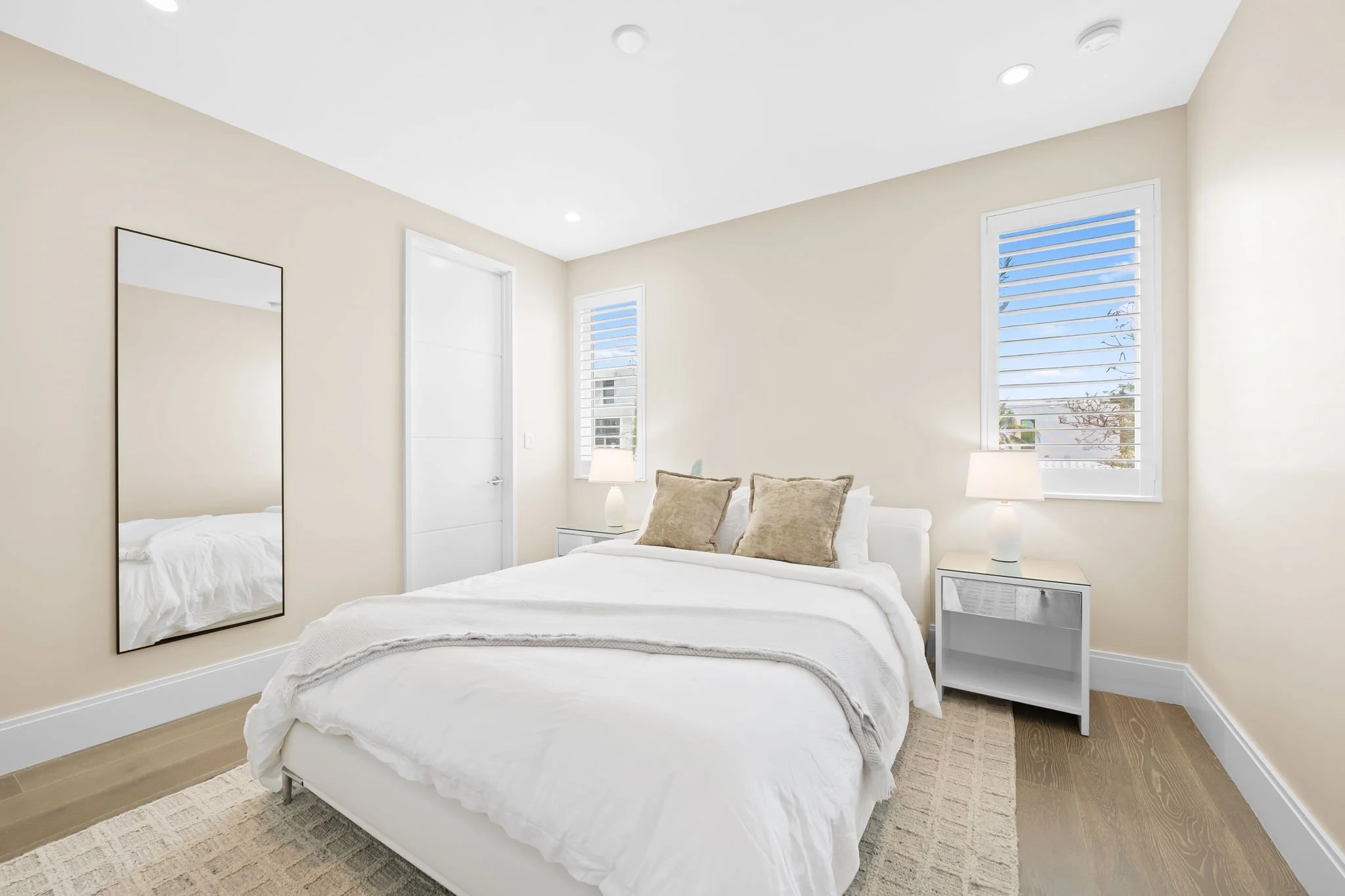 Minimalist bedroom with statement mirror and sunny views — Sun Haven Collection luxury vacation rental.