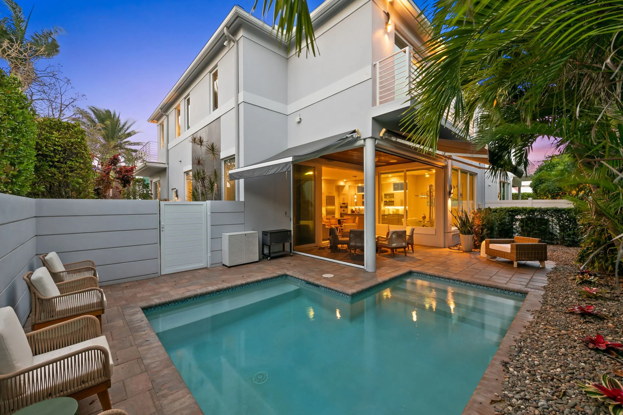 Poolside lounge at dusk with purple-pink sky — Sun Haven Collection luxury vacation rental.