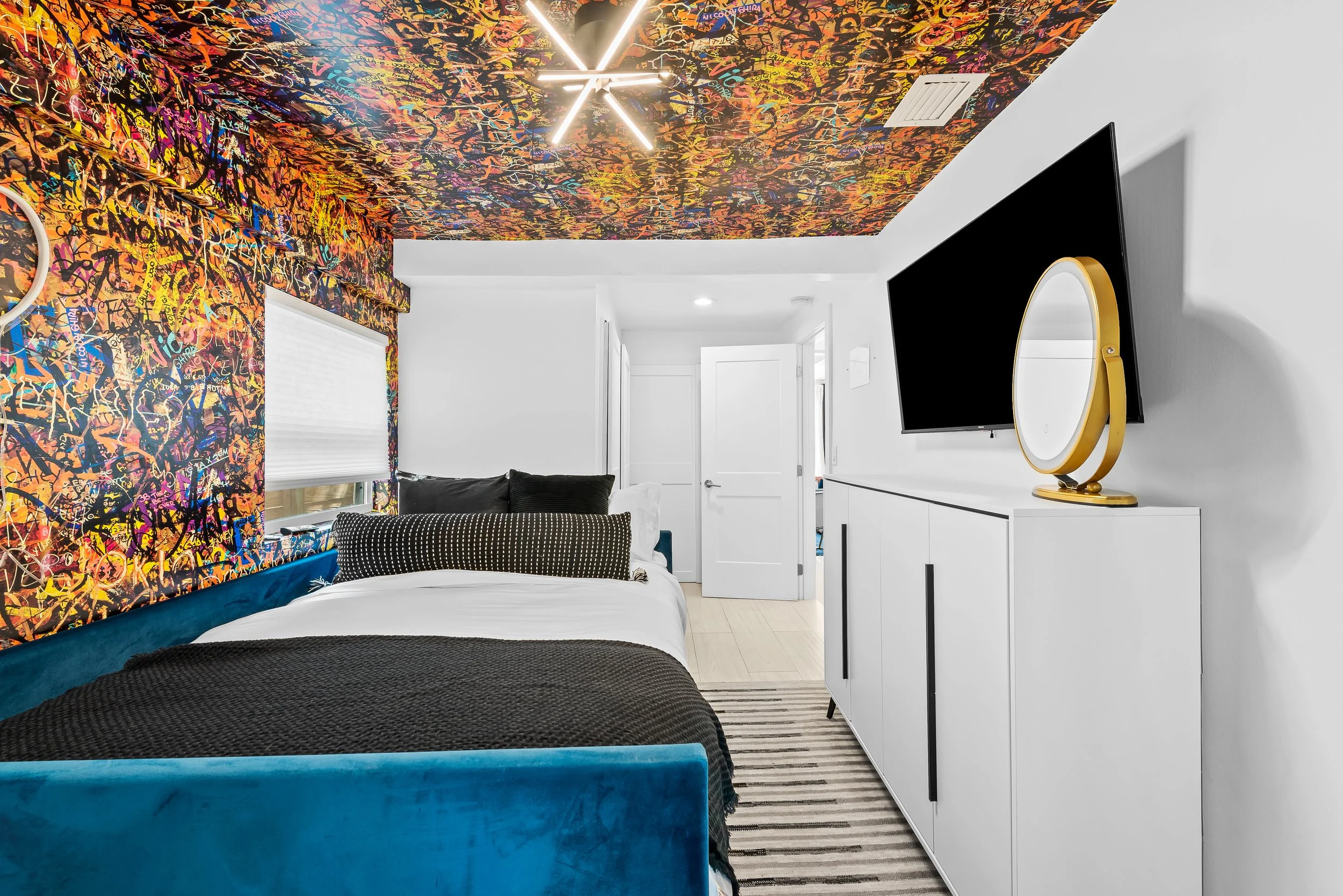 Graffiti-inspired bedroom with street art wallpaper and designer bed — luxury vacation rental, Sun Haven Collection.