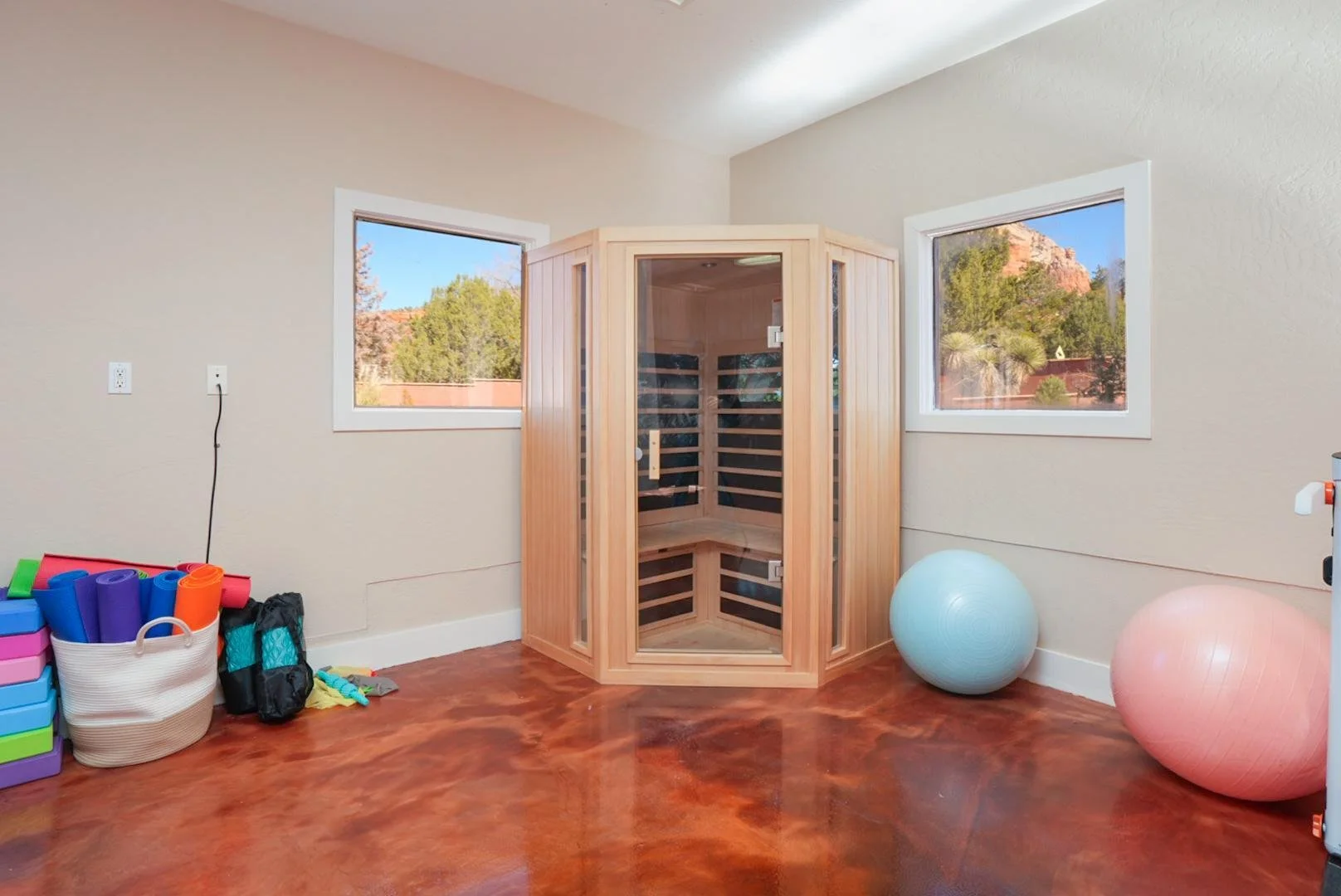 An indoor wellness room with wooden sauna, exercise balls, and storage containers.