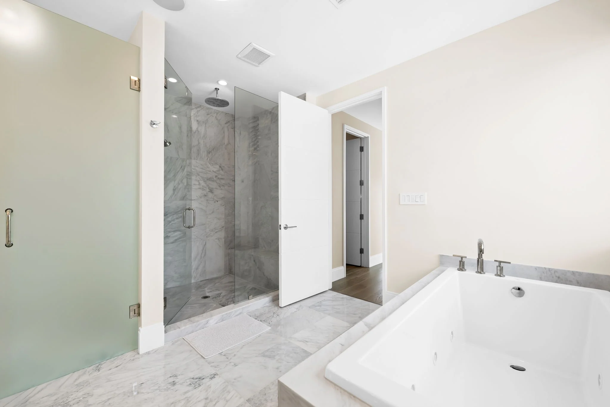 Marble bathroom with freestanding tub and glass rain shower — luxury vacation home, Sun Haven Collection.