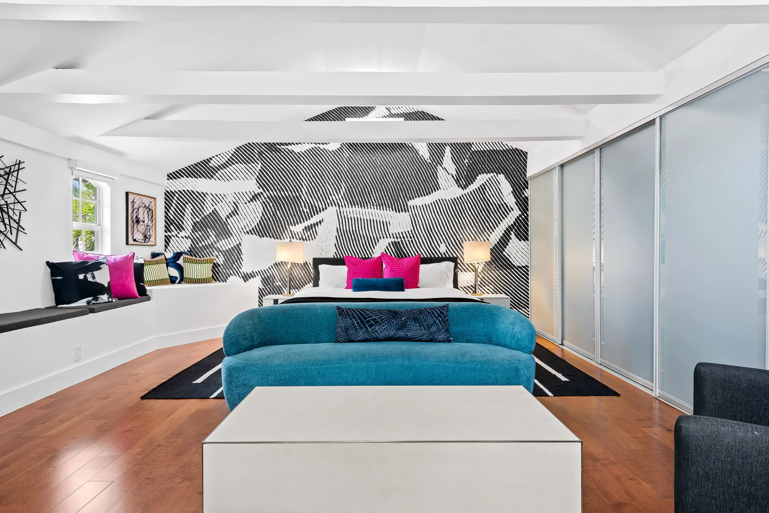 Contemporary living room with curved wall, abstract art, and pool views — Sun Haven Collection vacation home.