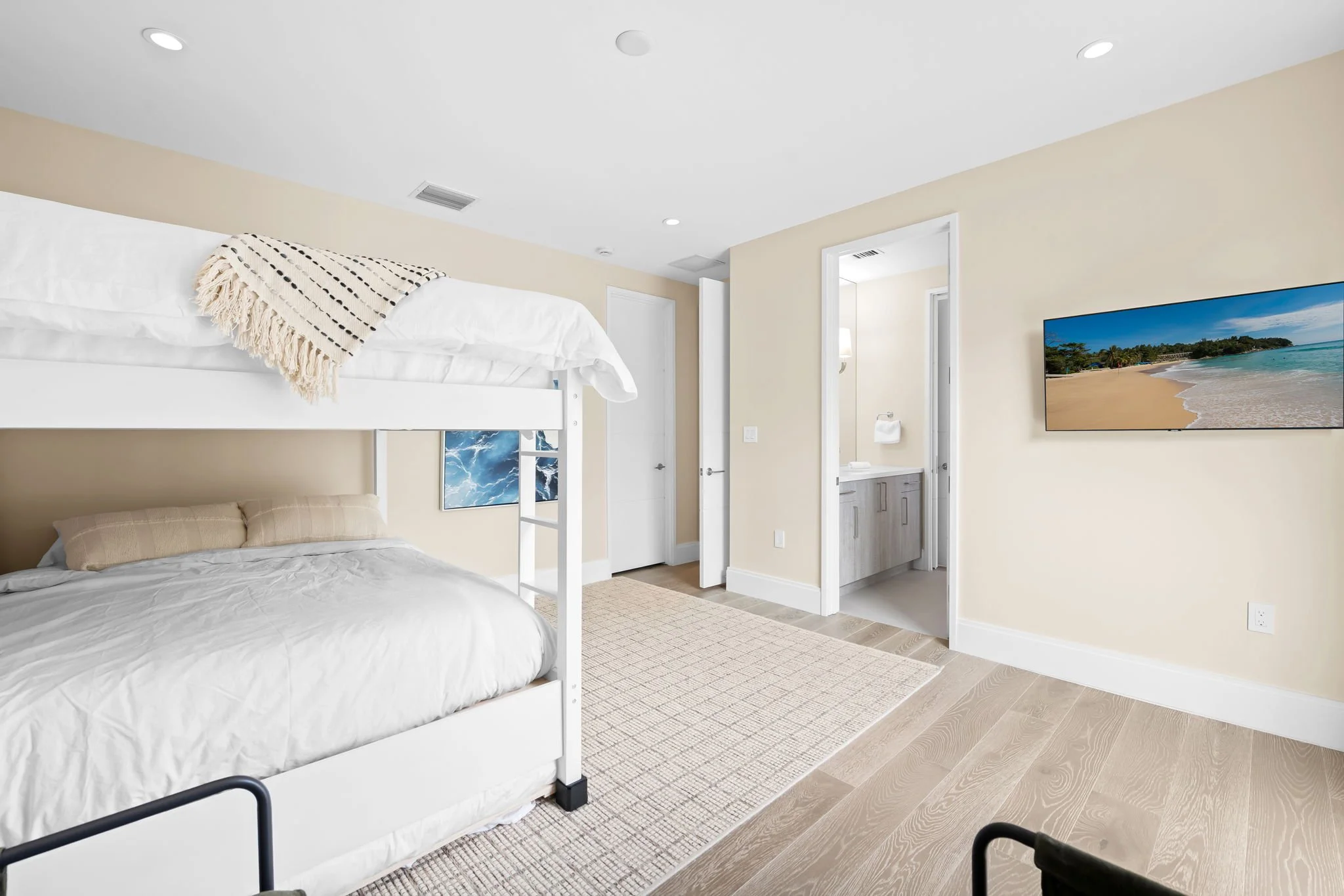 Kids' bunk room with beach-themed TV and hardwood floors — family vacation rental, Sun Haven Collection.