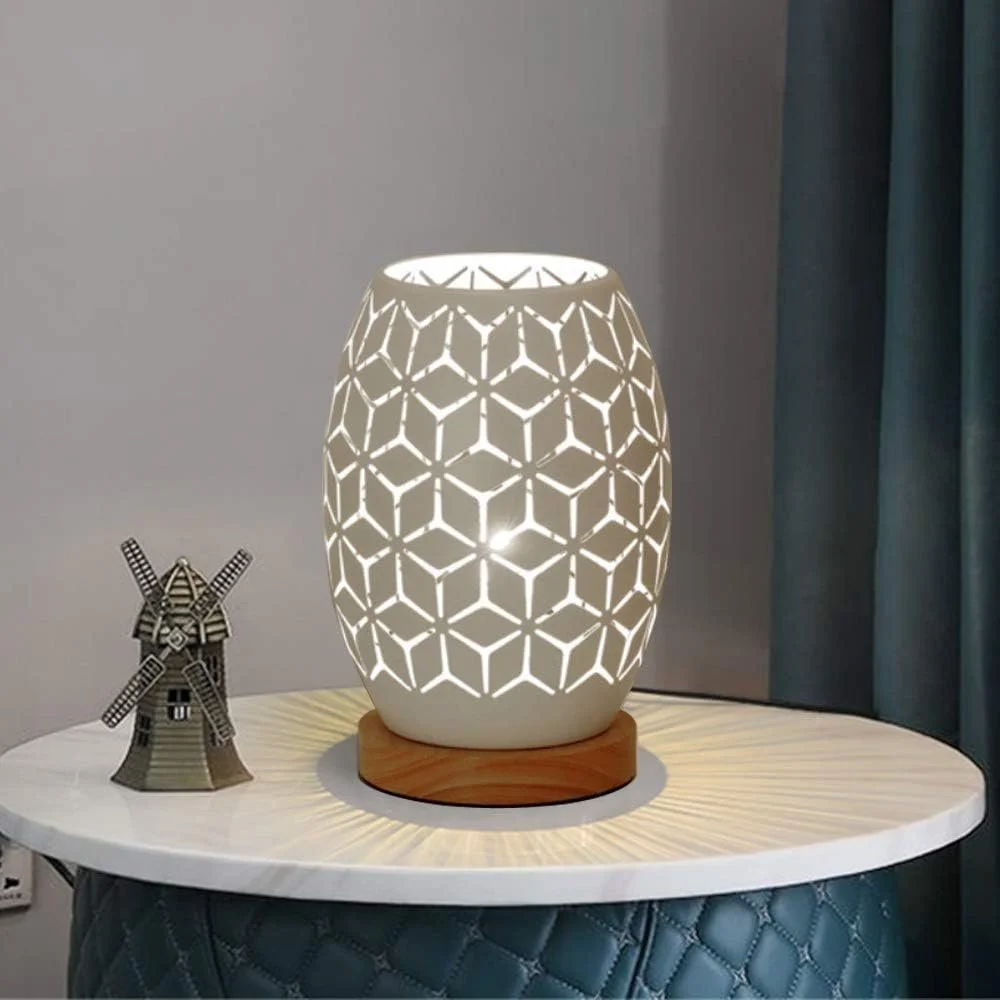 A white decorative lamp with a geometric pattern on a round table, next to a small windmill figurine.