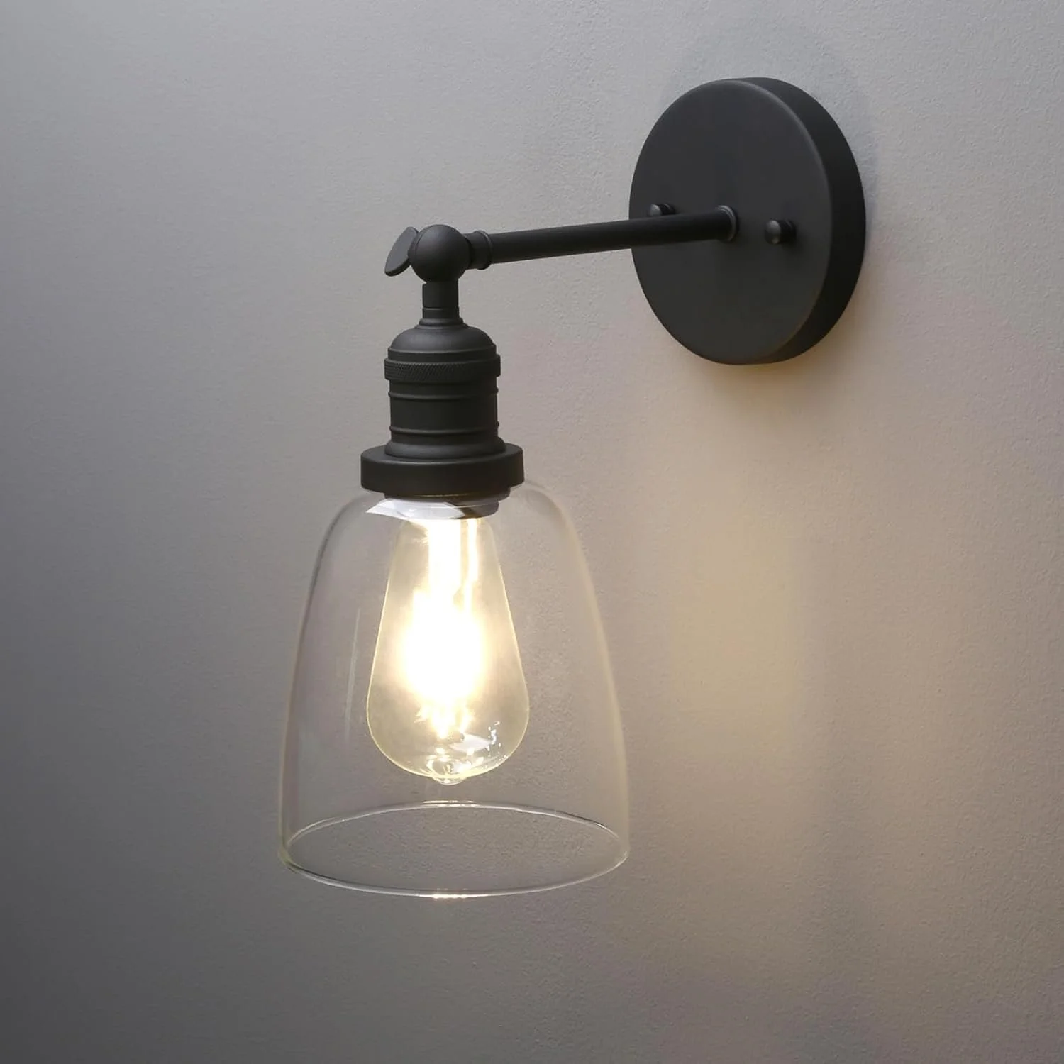 Black wall-mounted lamp with exposed light bulb and a glass shade.