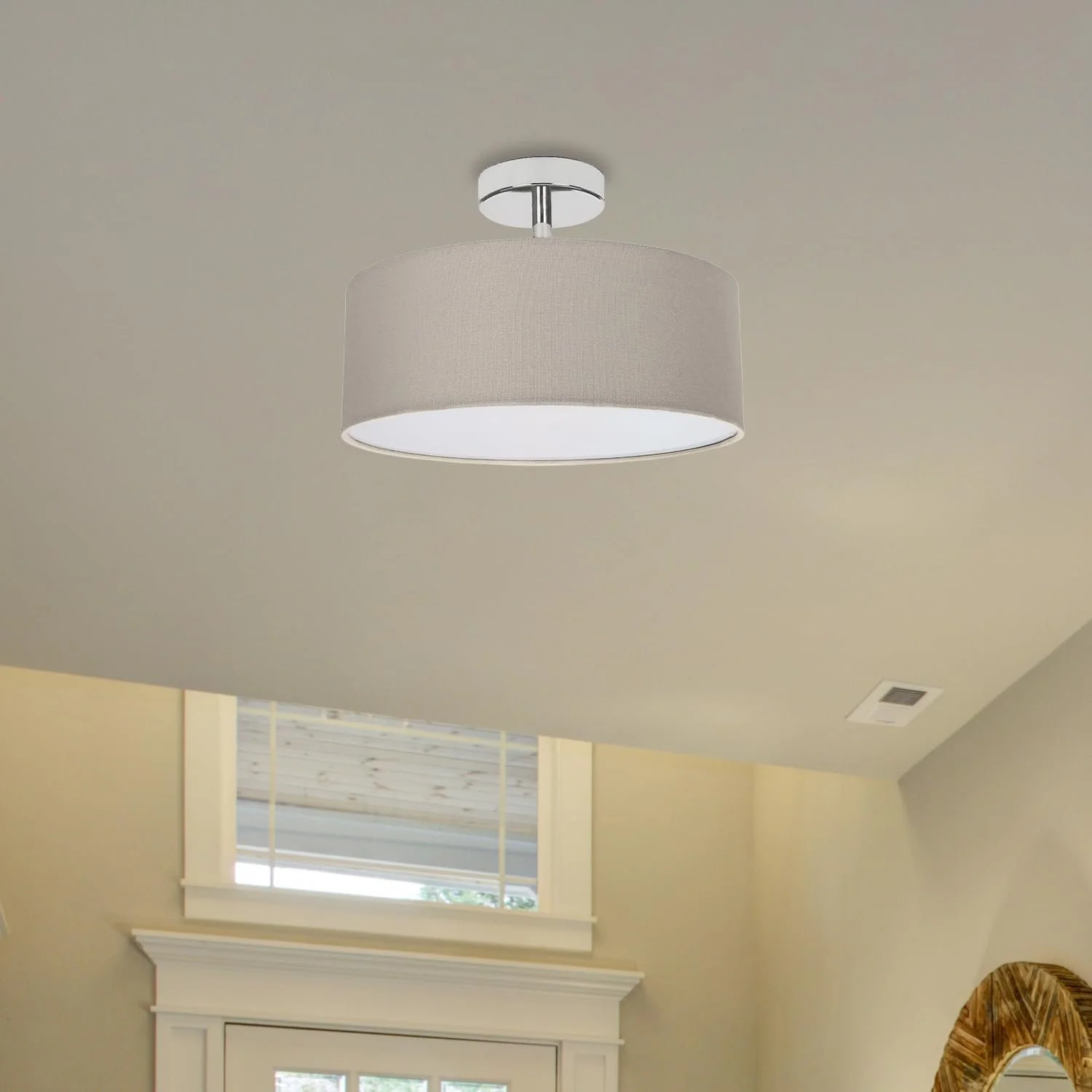 Ceiling light fixture with a fabric drum shade in a room with a window and decorative mirror.