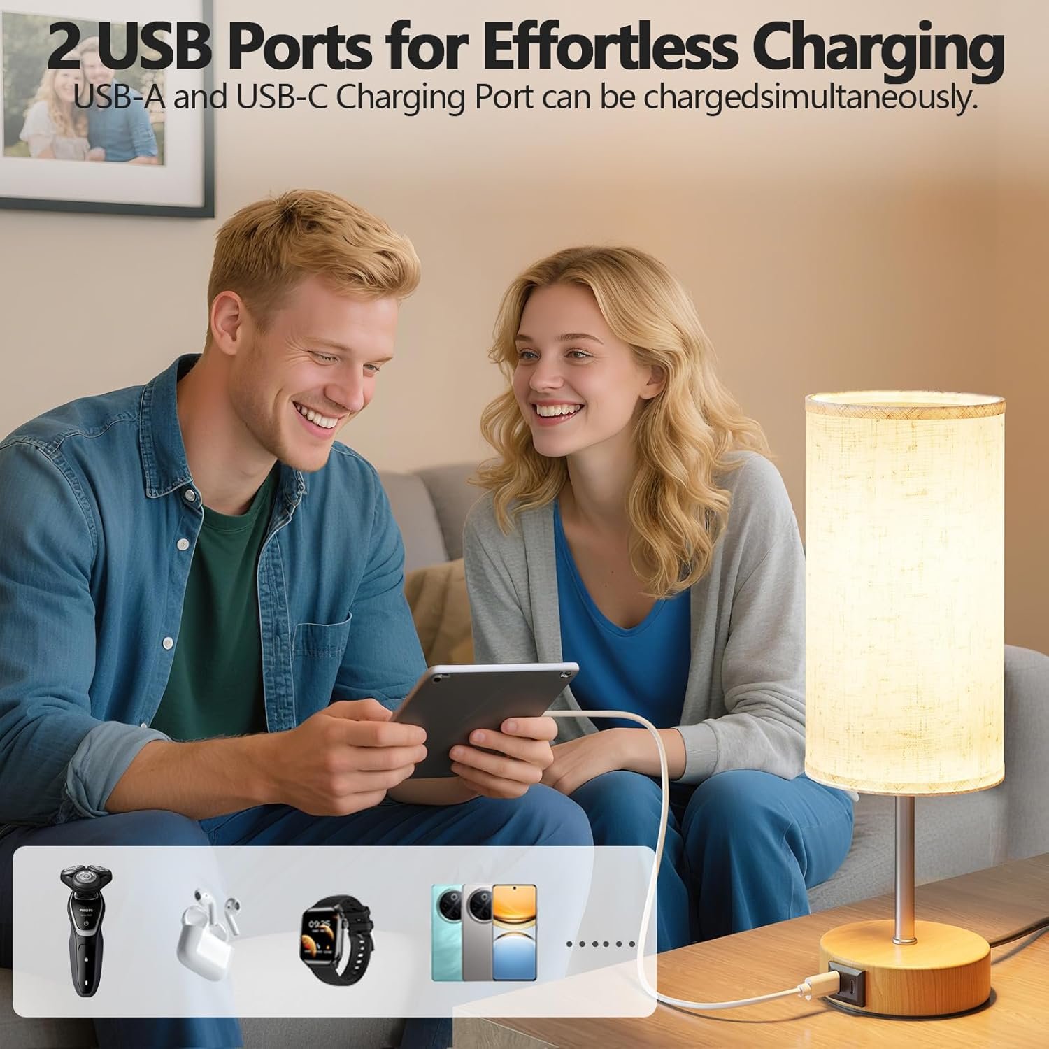 A man and woman sitting on a couch, smiling, as the man holds a smartphone connected to a charging cable. There is a lamp on a table next to them. The image promotes two USB ports for effortless charging, with icons of a shaver, earbuds, smartwatch, 