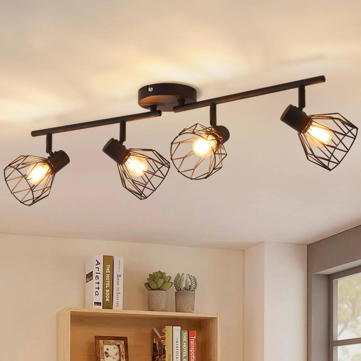 Modern ceiling light fixture with four exposed bulbs in geometric wire cages, mounted on a black metal track on a white ceiling.