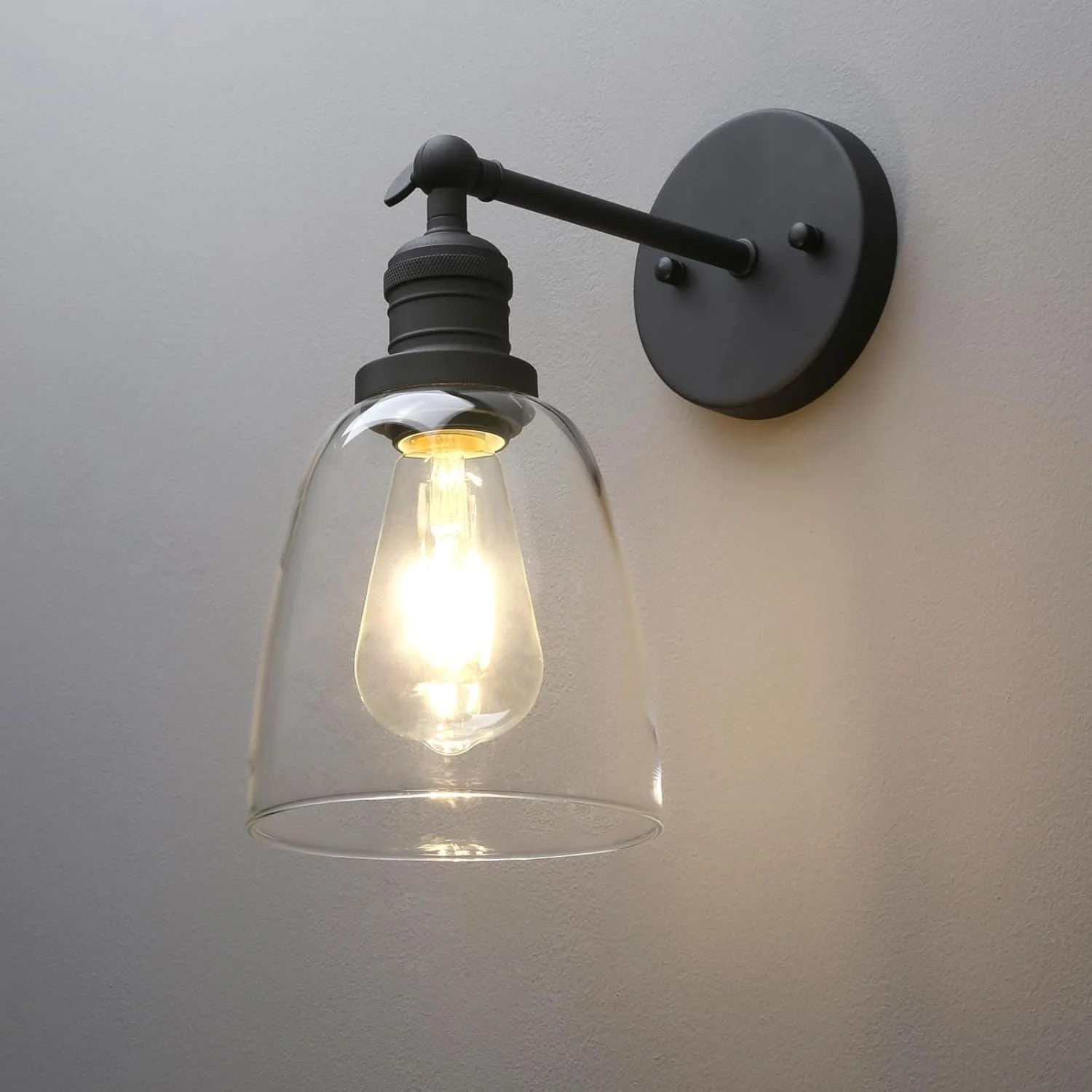 Wall-mounted black industrial-style sconce with clear glass shade and exposed light bulb.