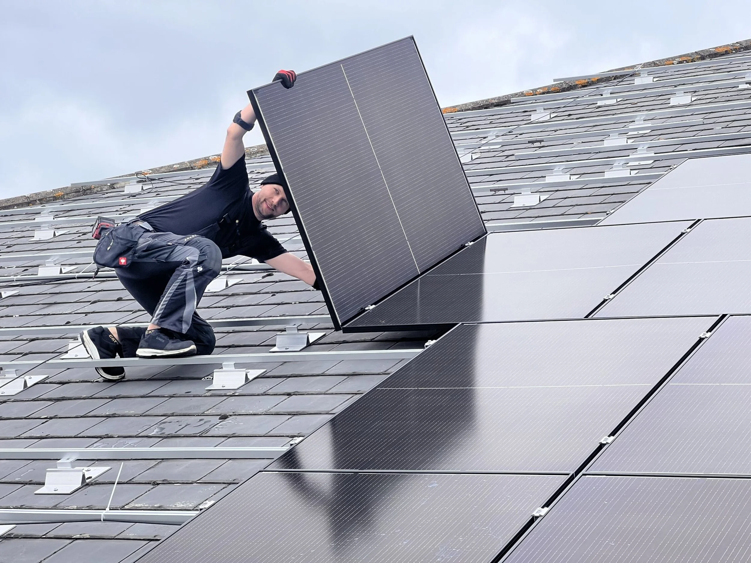 A man installing or maintaining solar panels on a sloped roof.