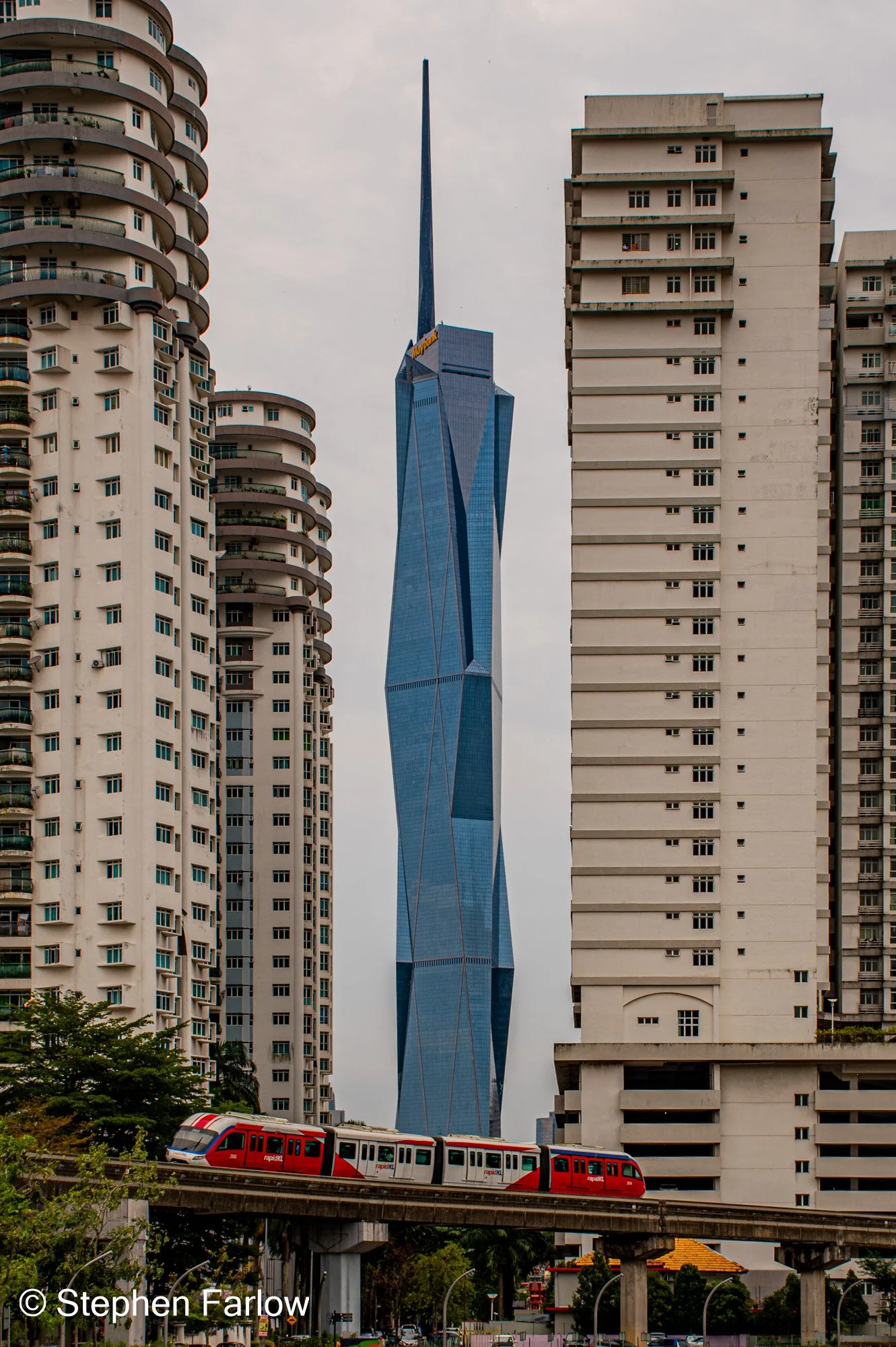 Merdeka 118 framed between buildings with monorail train