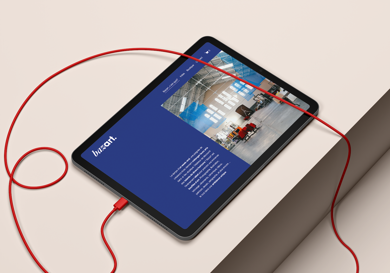 Tablette avec une page web de Bazart, montrant une photo d'intérieur d'une salle d'exposition ou de musée, avec des fenêtres hautes et des chaises rouges.