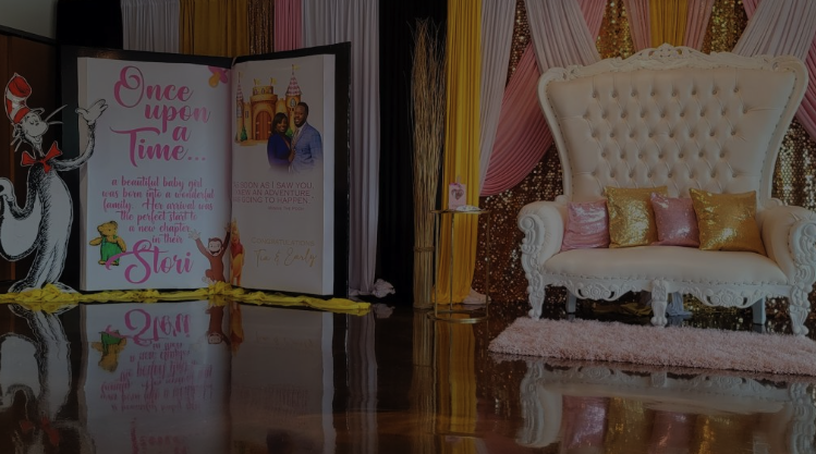 Party setup with a large display board featuring 'Once upon a Time' theme, a white ornate sofa with pink and gold pillows, and colorful curtains in the background.