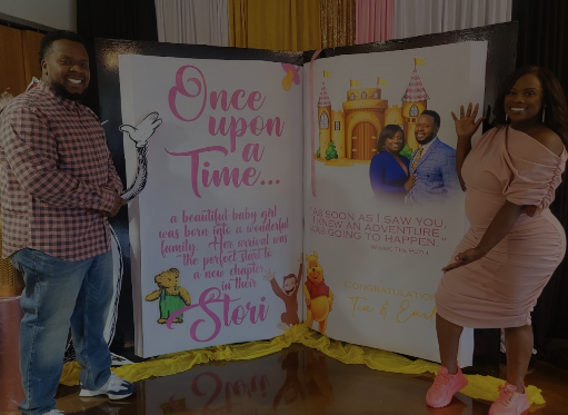 Two people standing next to a large, opened storybook display with colorful illustrations and text, celebrating a fairy tale theme.