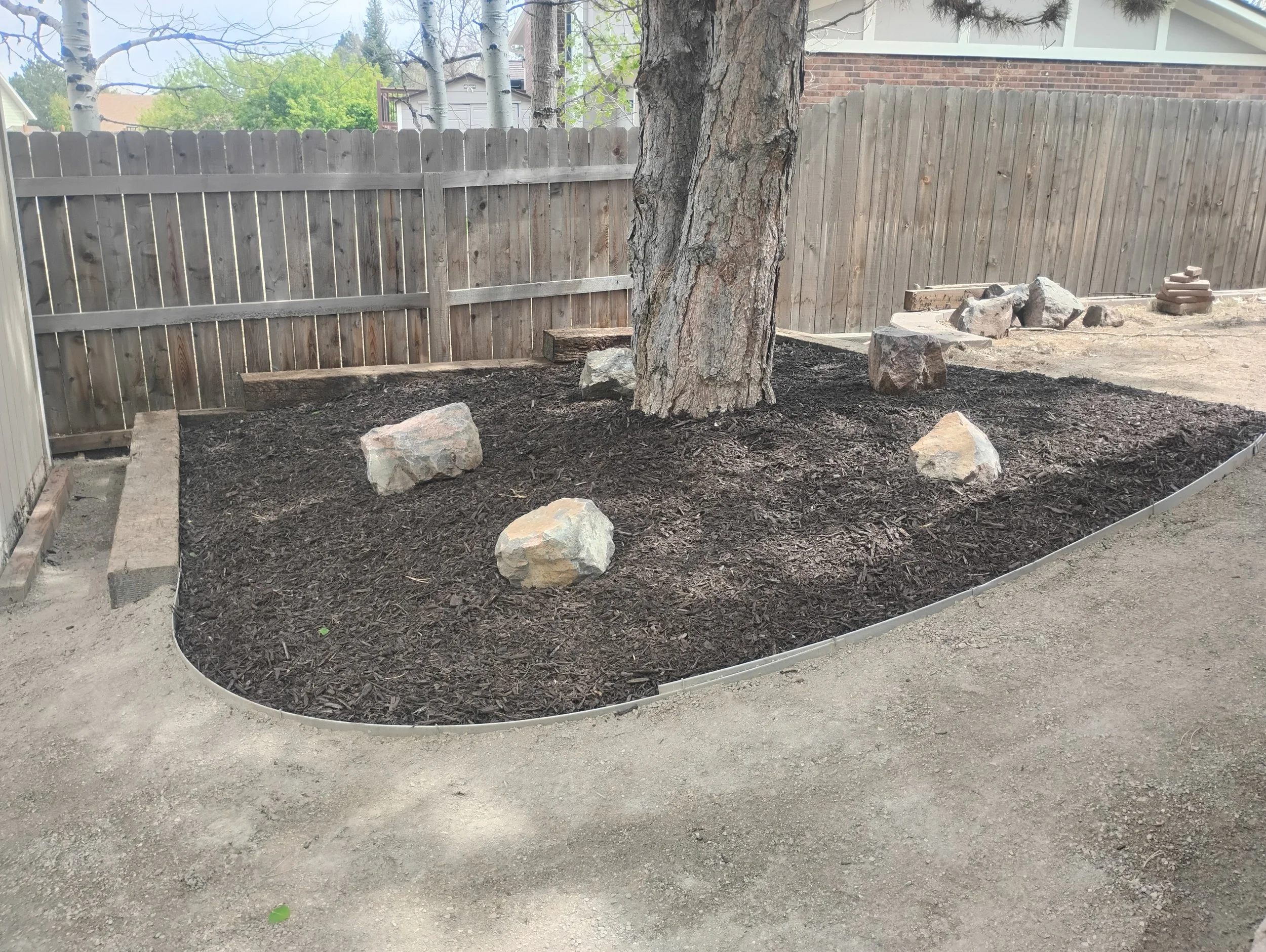 A mulch bed which was refreshed around an existing tree with some decorative boulders.