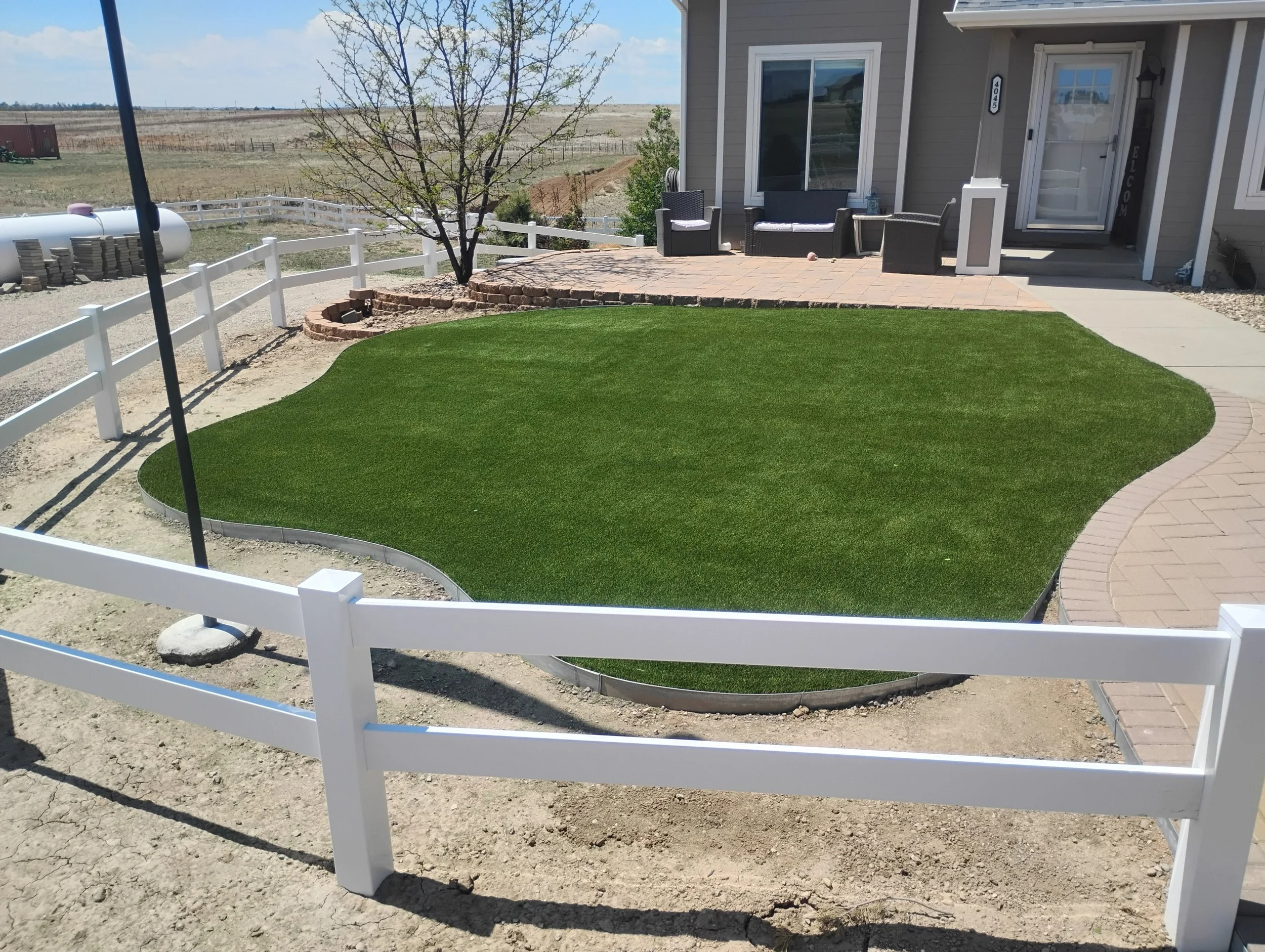 Artificial turf installed in an oddly shaped yard in front of a house.