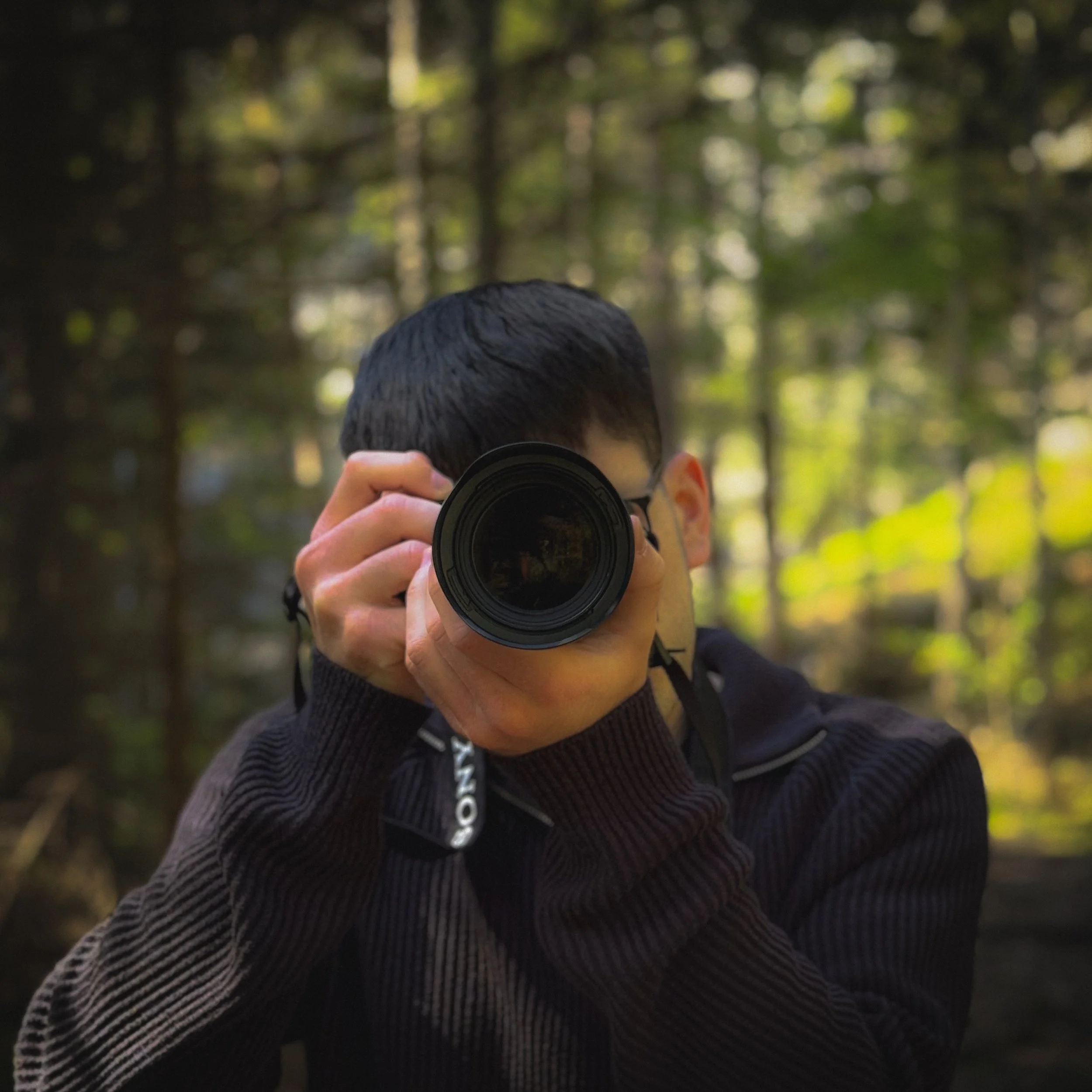 Fotograf in einem Wald nimmt ein Foto mit einer Kamera auf.