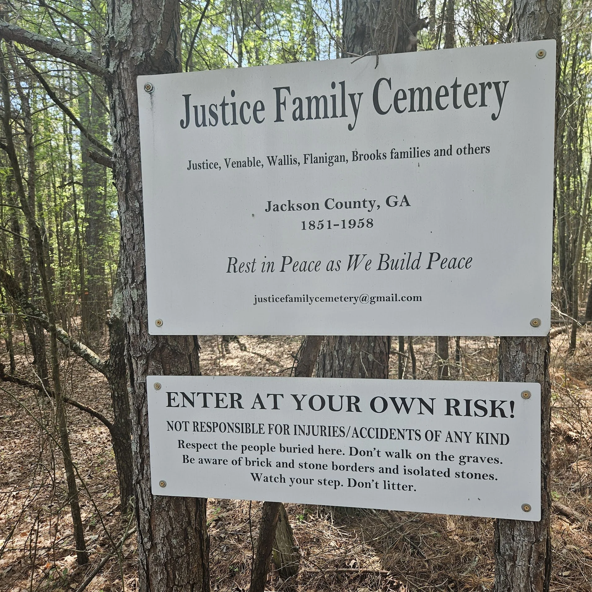 Sign at Justice Family Cemetery in Jackson County, Georgia, with rules and contact information, mounted on a tree in the woods.