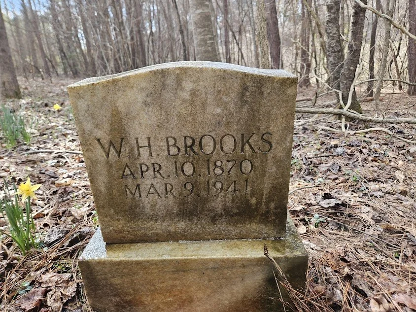Gravestone with inscription for W. H. Brooks, born April 10, 1870, died March 9, 1941, in a wooded area.