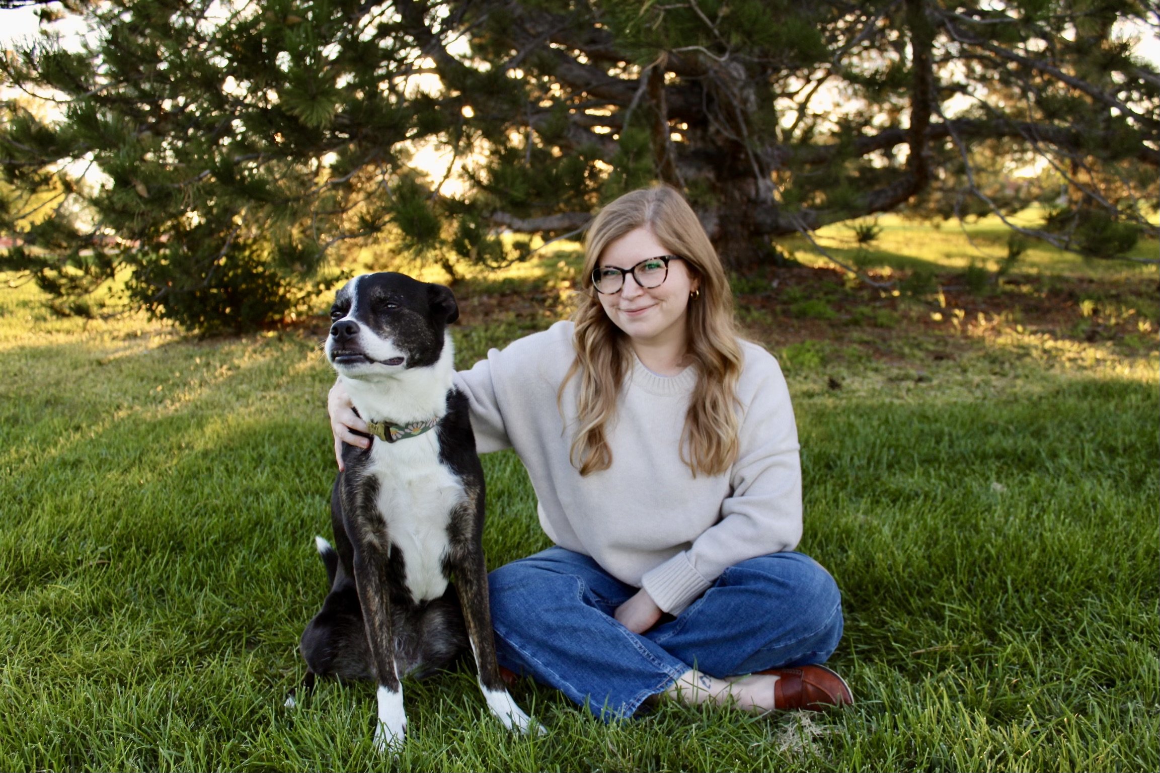 Kelsey McCamon, Licensed Professional Counselor, sitting outside with her dog in soft natural light