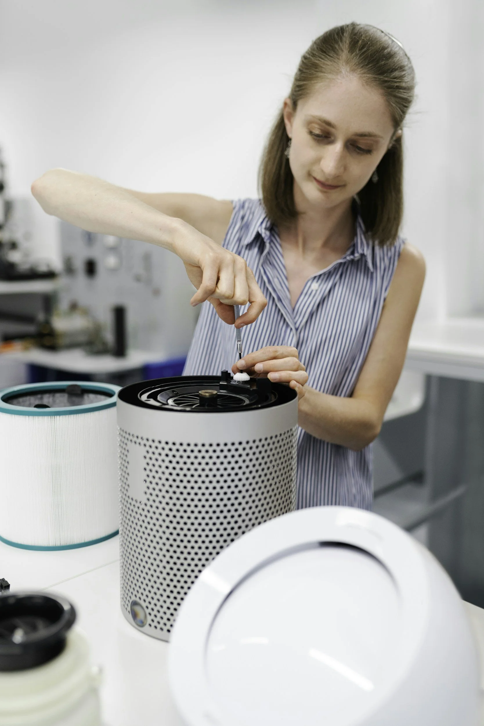 A woman repairing a device in a laboratory, using a screwdriver.