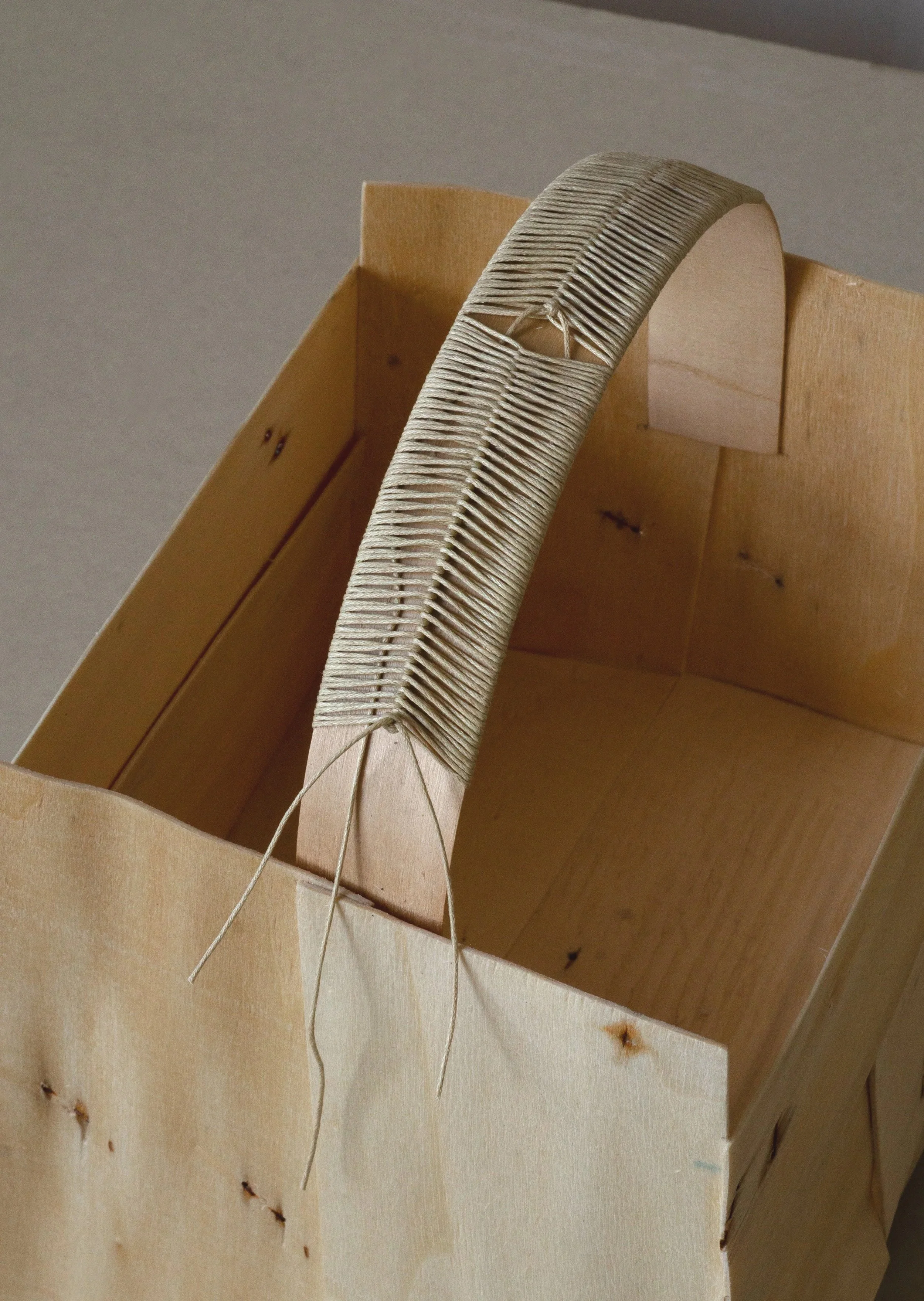 A wooden box with a curved piece of wood that has a series of evenly spaced, raised ridges, with some strings attached, inside the box.