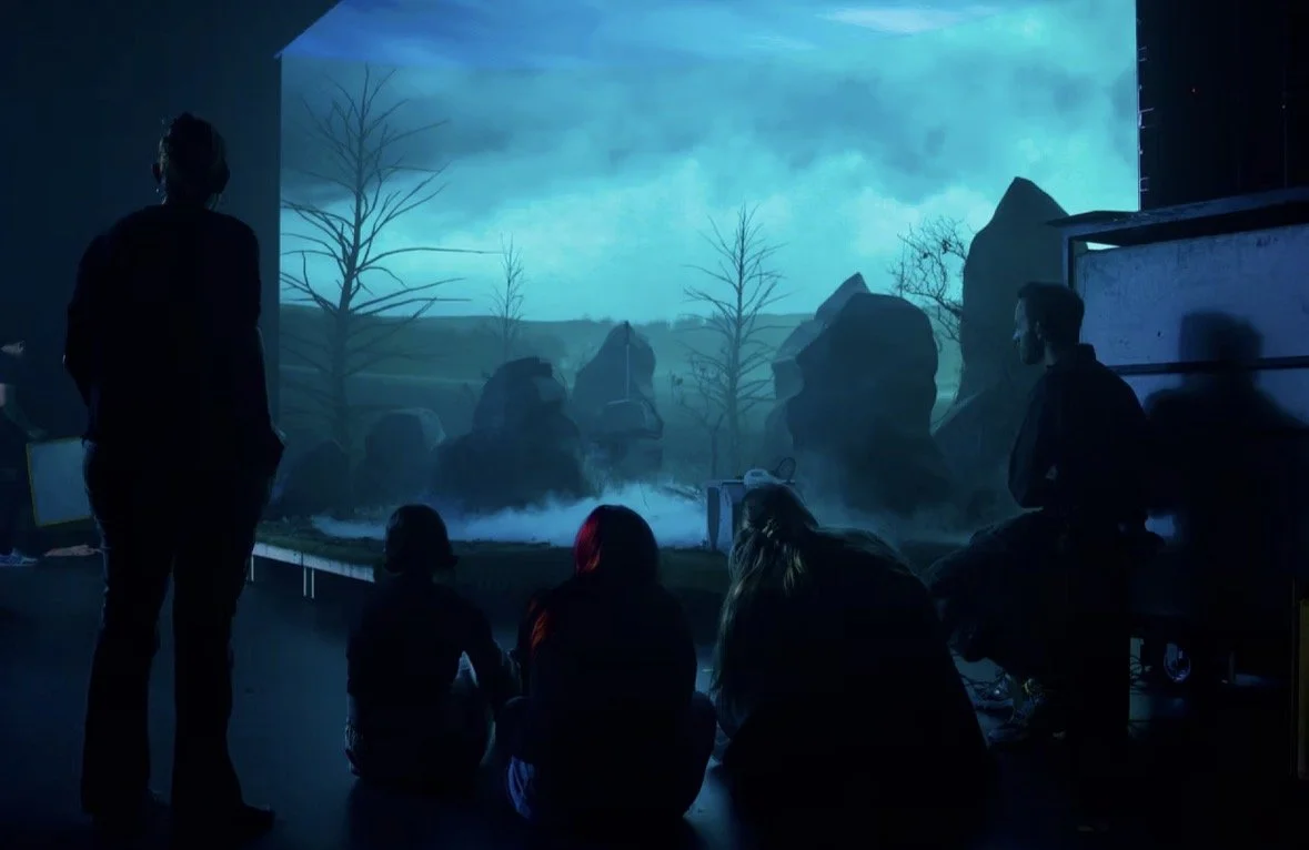 People watching an aquatic show with a large tank, rocks, and trees inside, simulating a natural underwater environment.