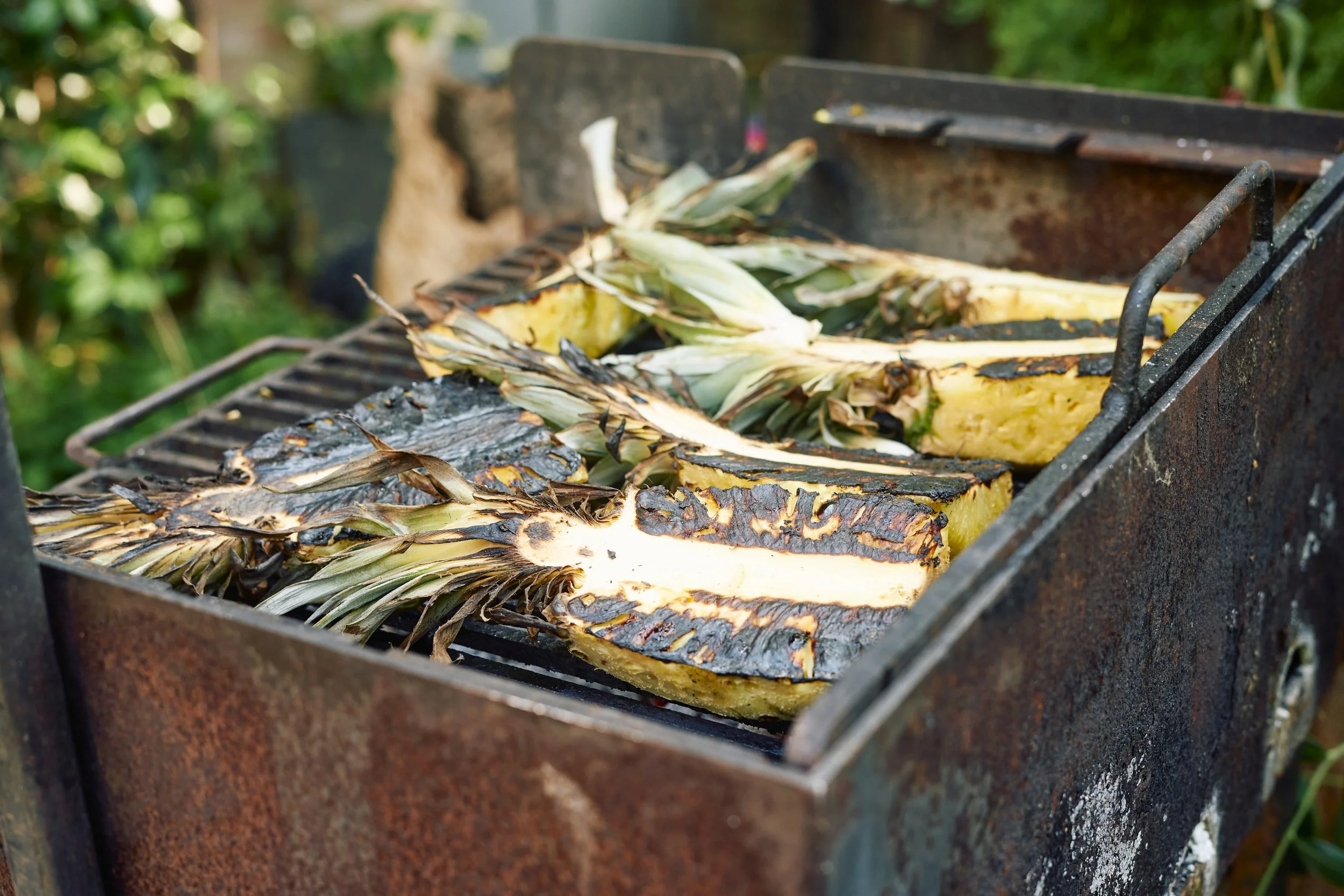 Pineapple slices being grilled on a barbecue.