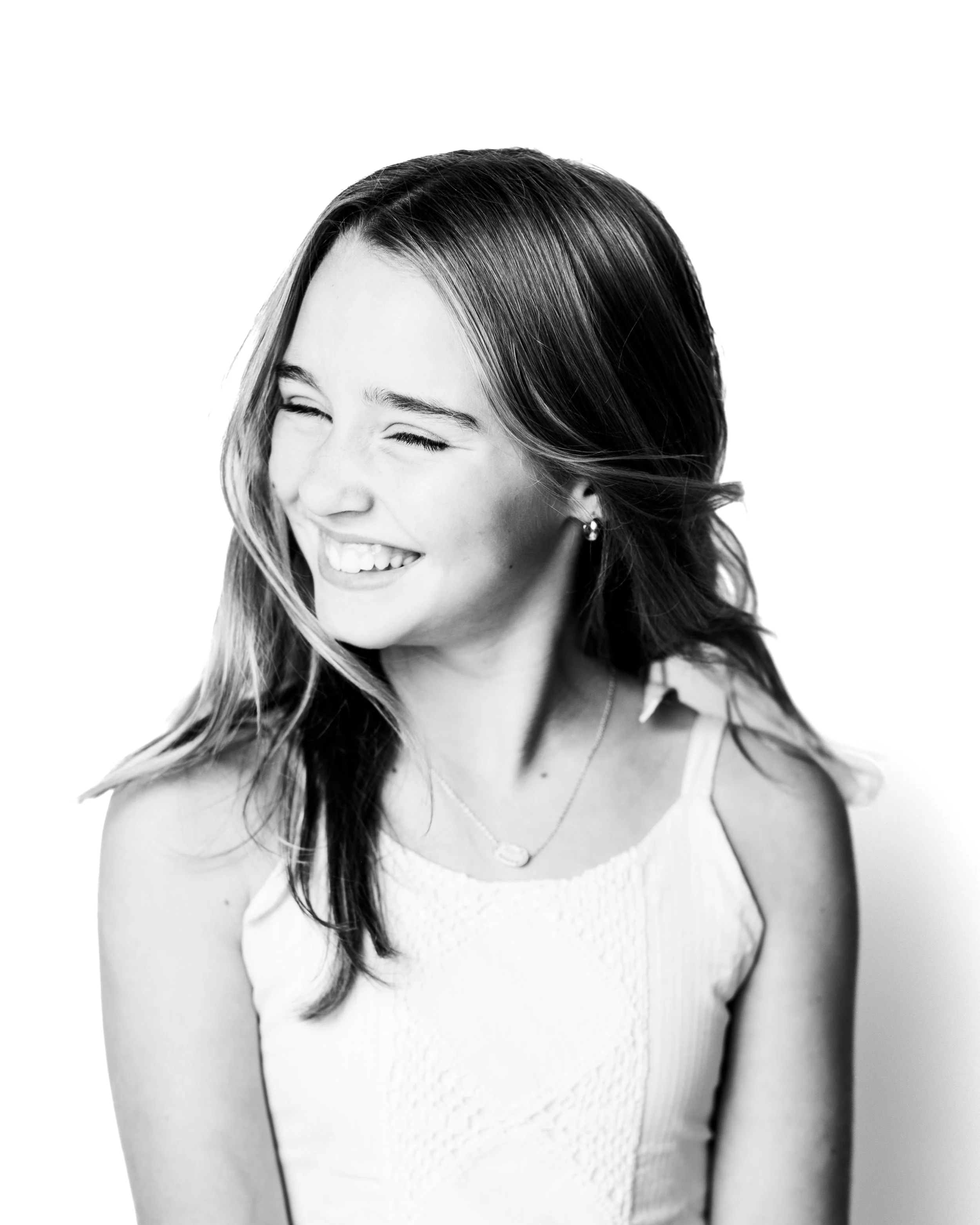 Black and white portrait of a young woman with long hair, smiling and looking to her right.