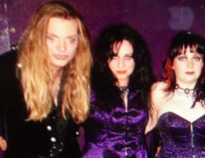 Tracie Law, Pam Chowhan and Diane Fox from Symphony of Pain with dark and curly or wavy hair, dressed in purple, black, and dark colors, posing together in an indoor setting with purple lighting.