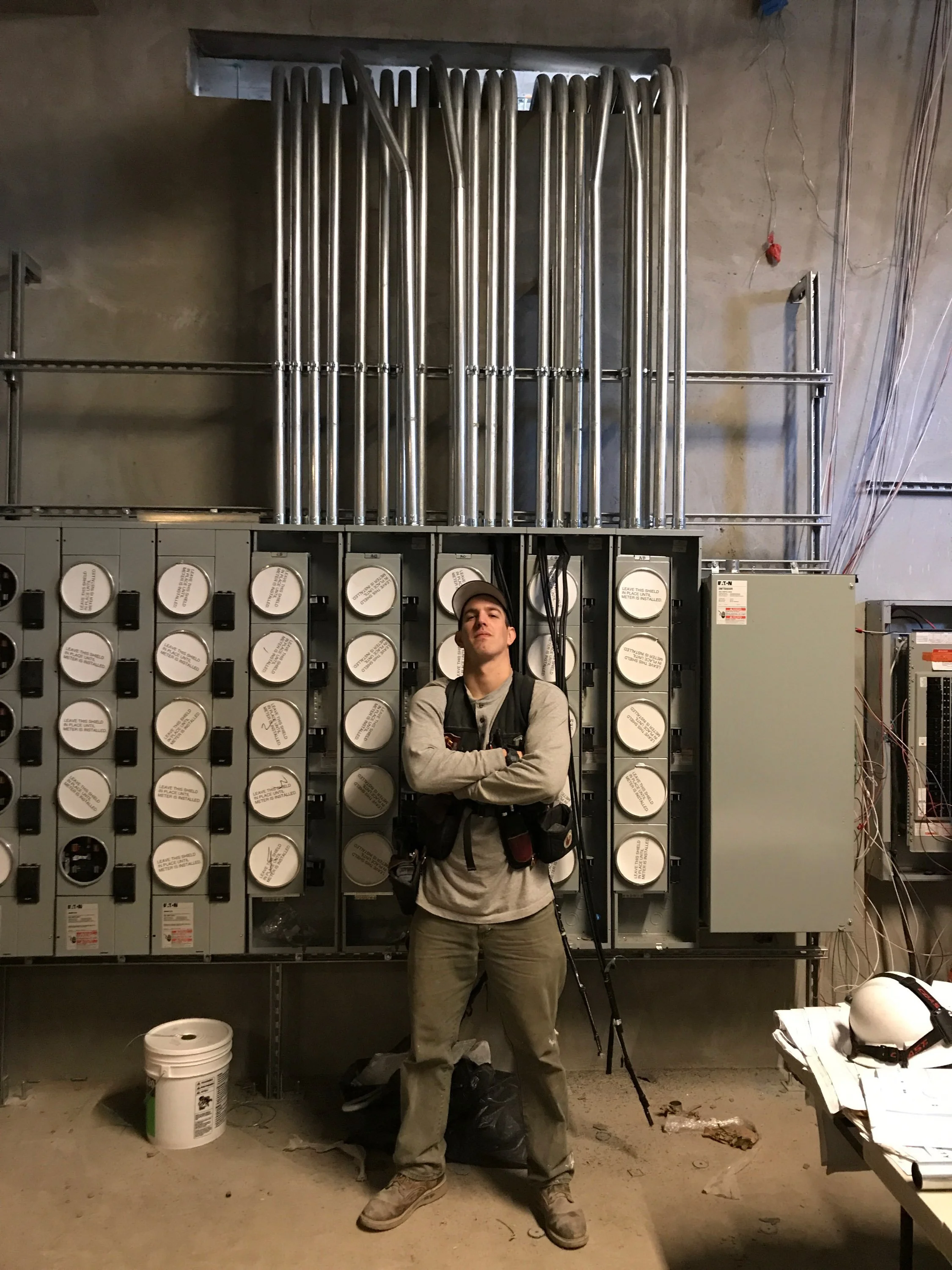 Collins Electric electrician beside a multi-meter bank and conduit, typical of new construction in Santa Rosa, CA.
