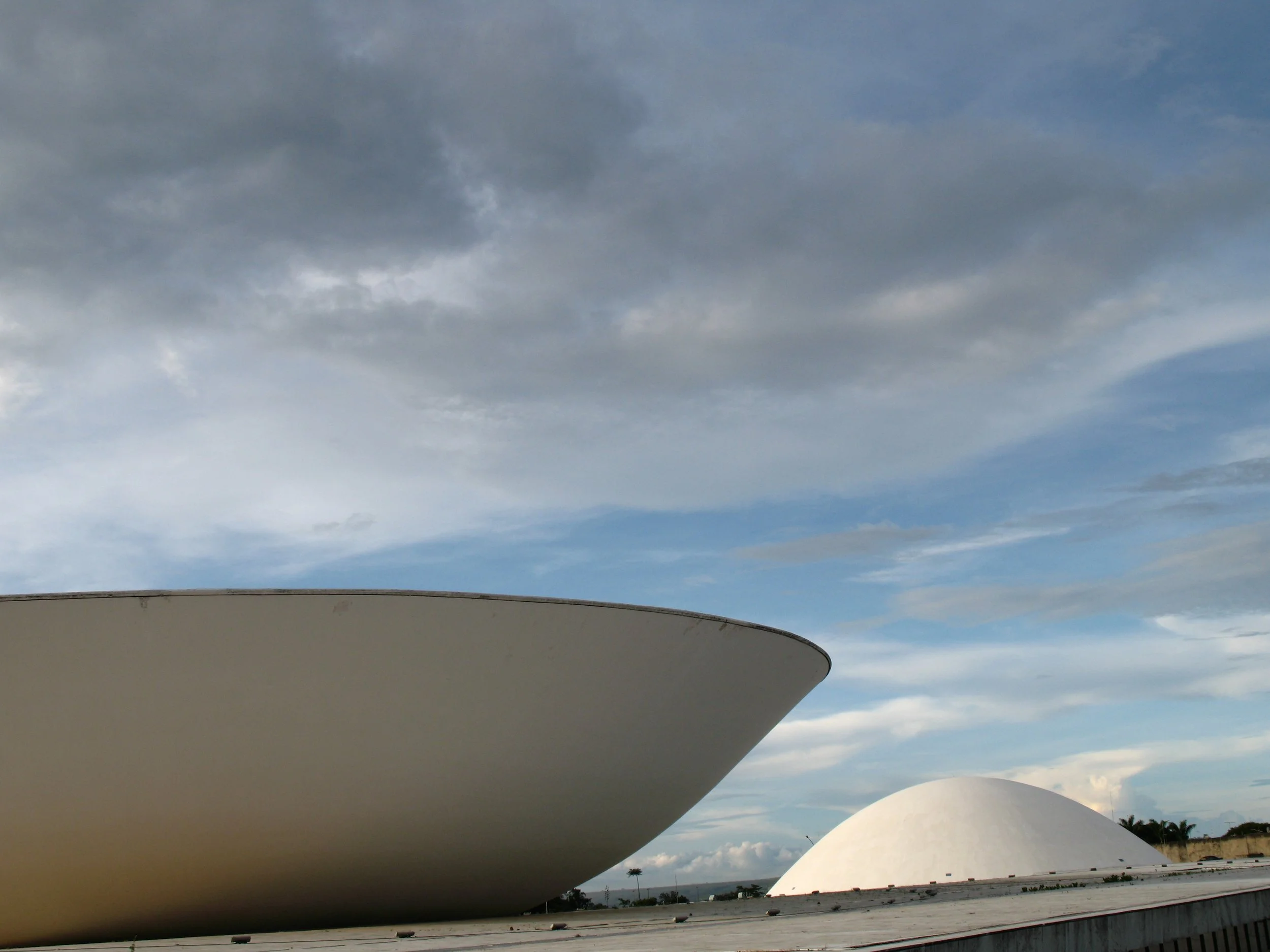 Edifícios futuristas brancos com formas arredondadas sob céu com nuvens. Brasília, Brasil.